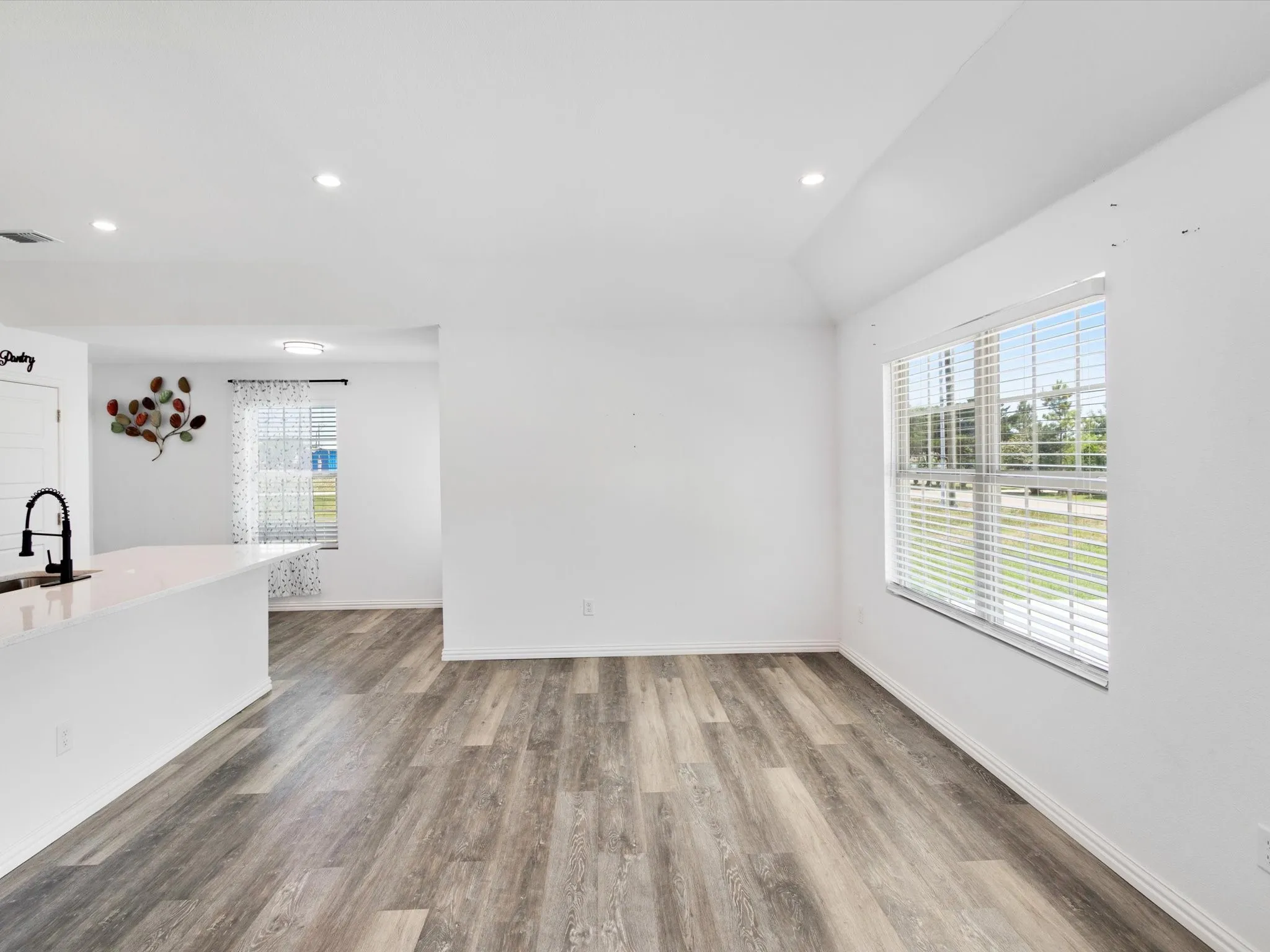 Open-concept living space with wood-finish flooring, white walls, and recessed lighting