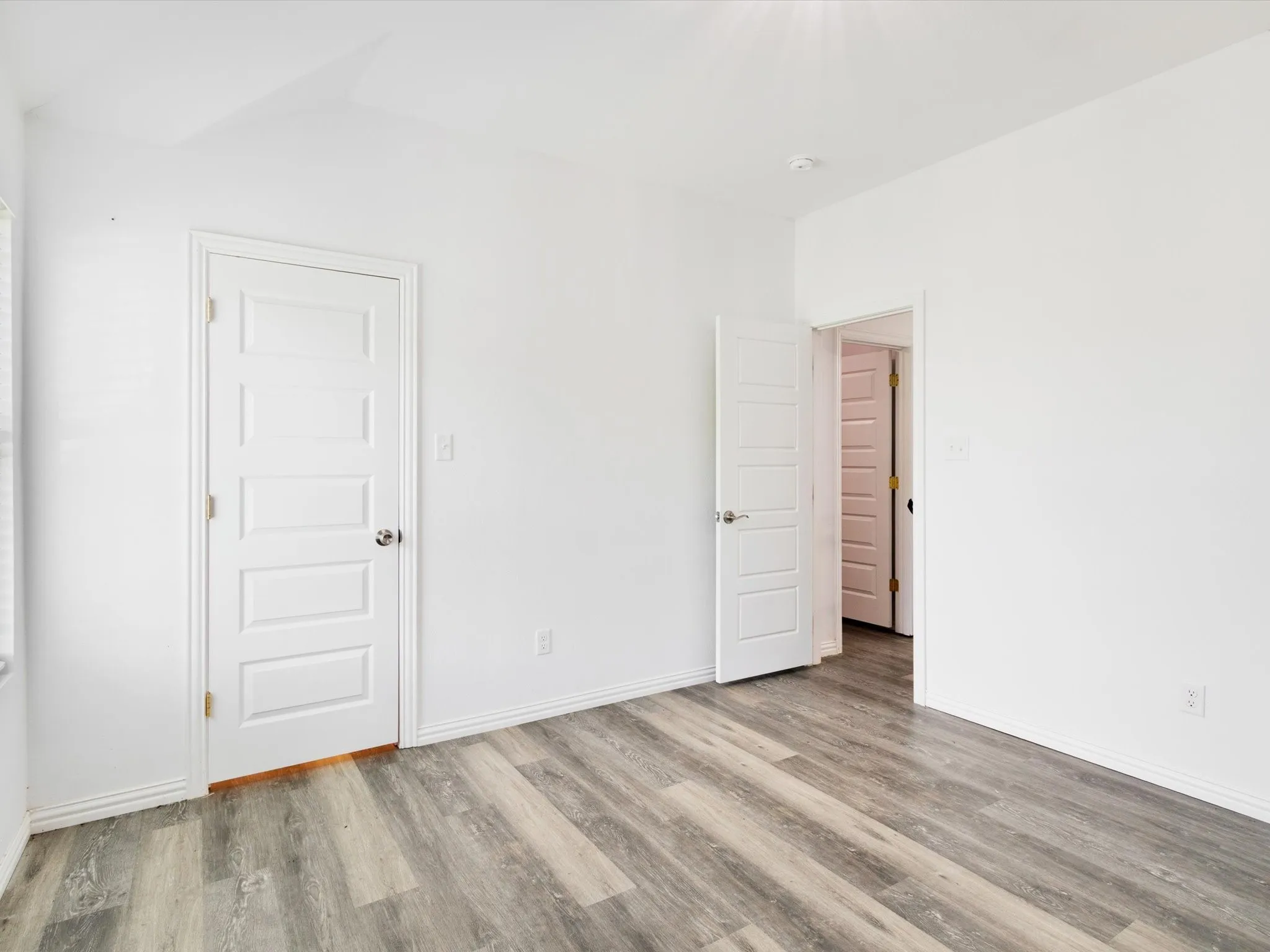 Light-filled room featuring wood-finish flooring and crisp white walls