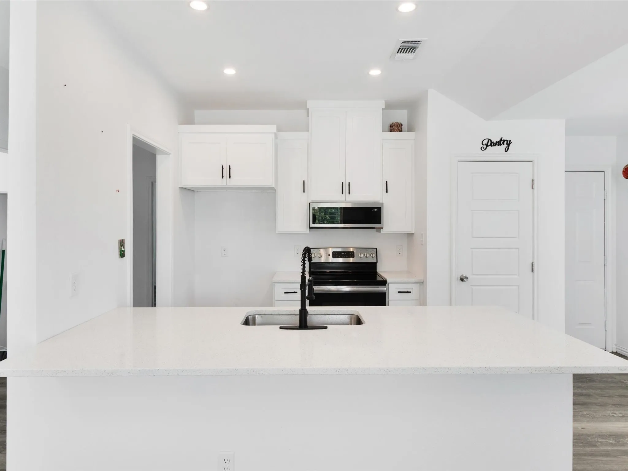 Modern kitchen featuring a spacious island with an undermount sink and black faucet