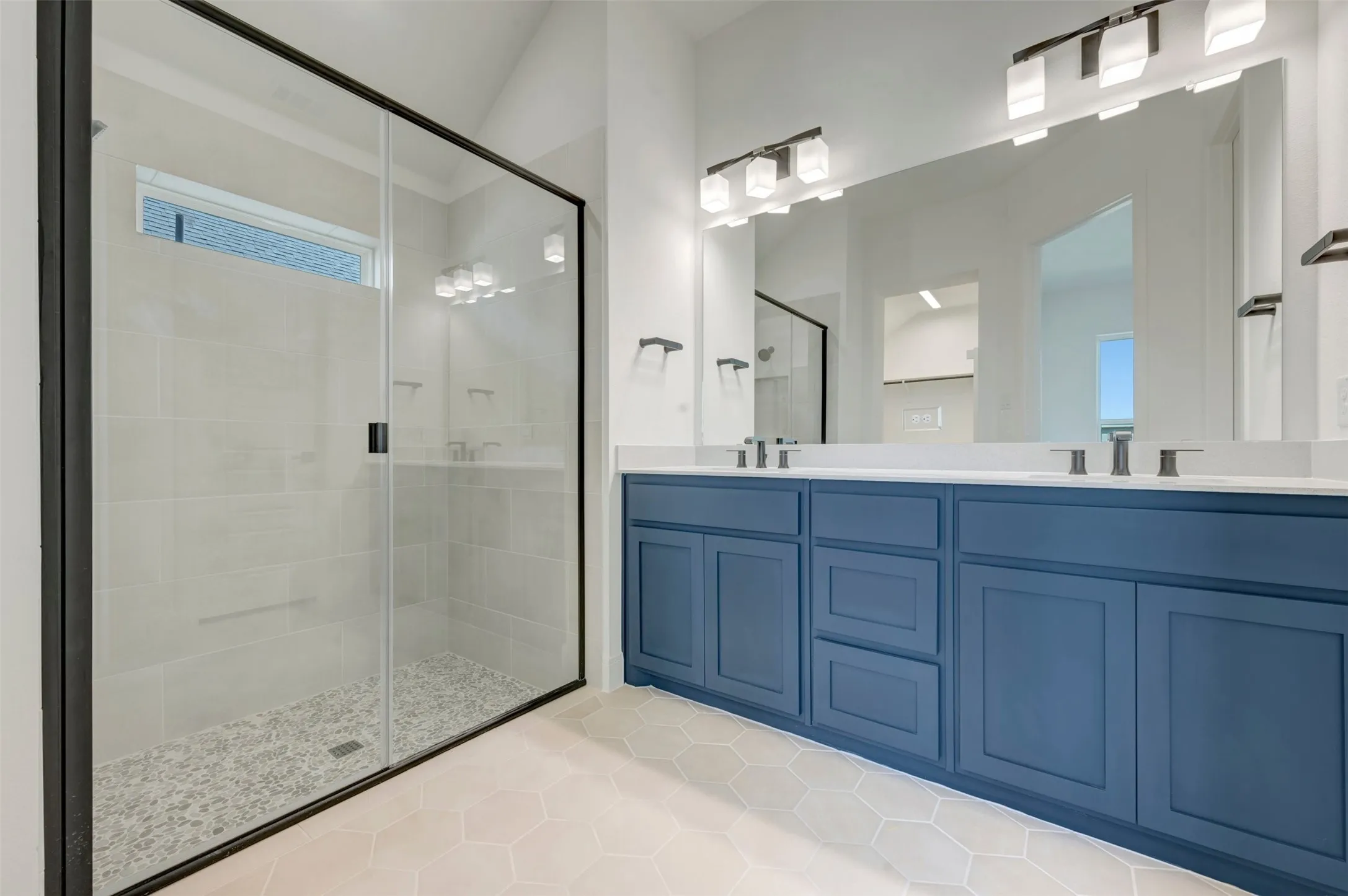 Walk-in shower with a glass enclosure and pebble-tile floor