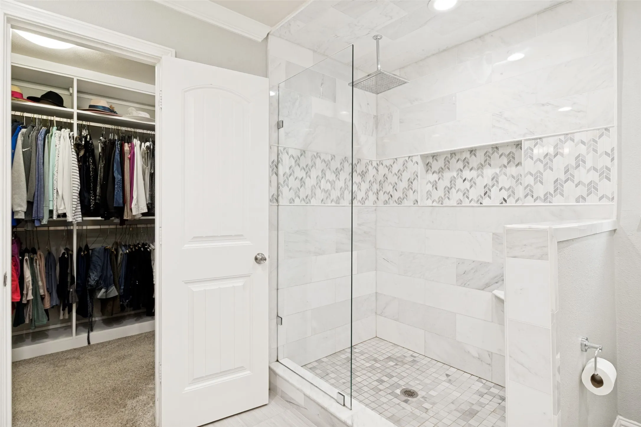 Primary bath frameless glass shower with rainhead, California Closets custom his and hers closets.