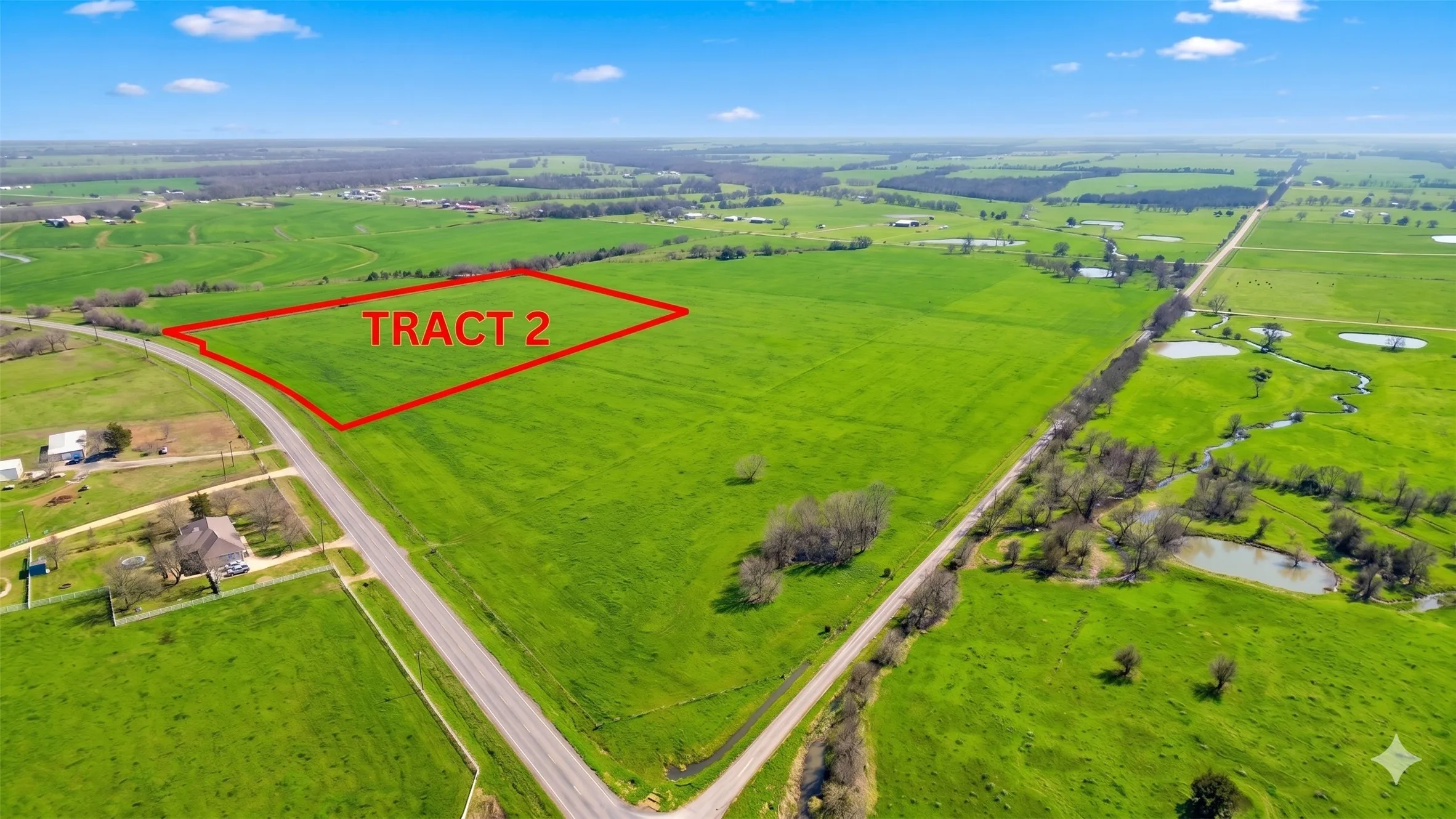 Expansive green acreage with defined boundary, bordered by a paved road