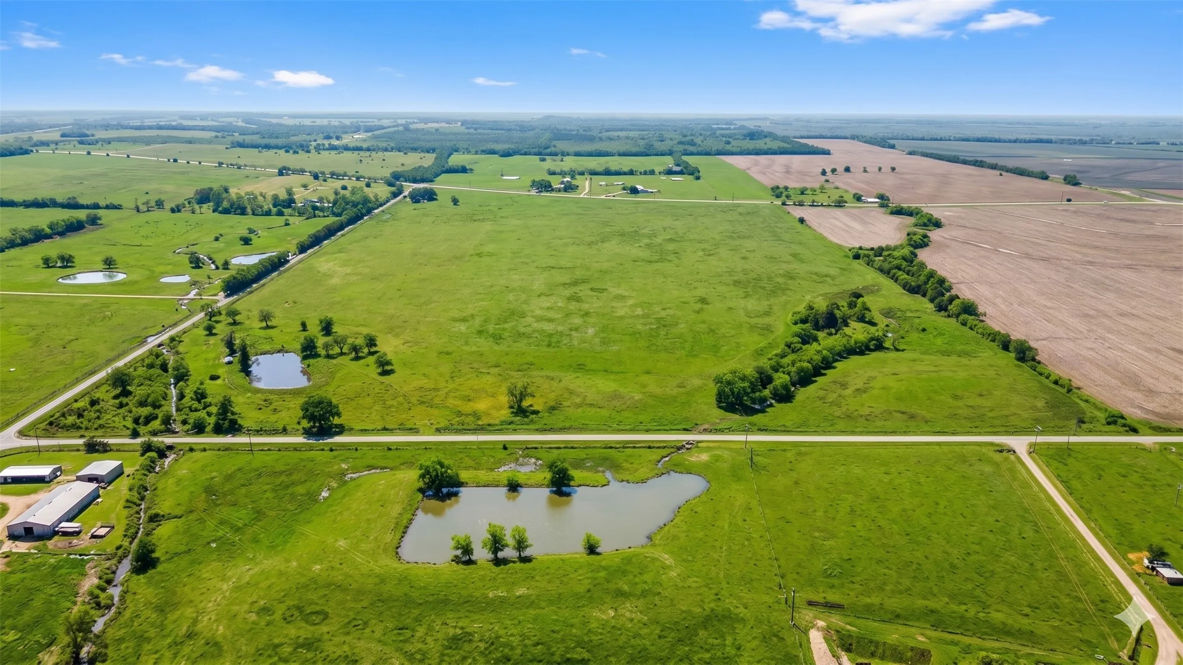 Expansive green acreage featuring multiple ponds and intersecting roadways