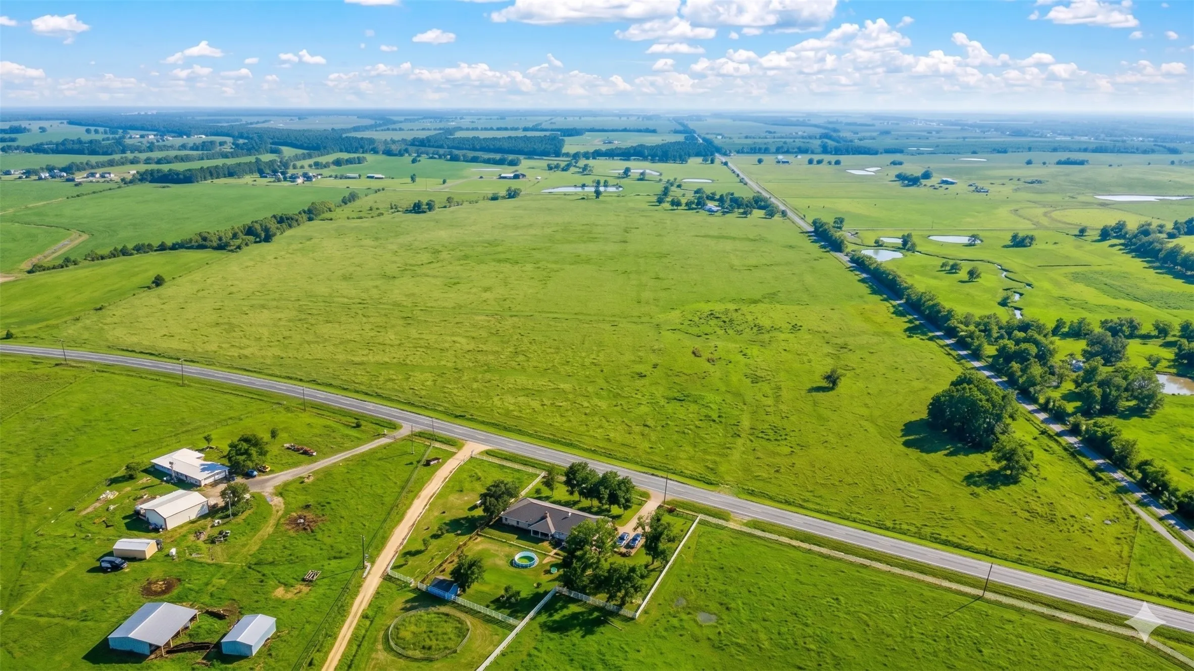 Expansive rural property featuring a single-story residence, multiple agricultural buildings, and a round pen