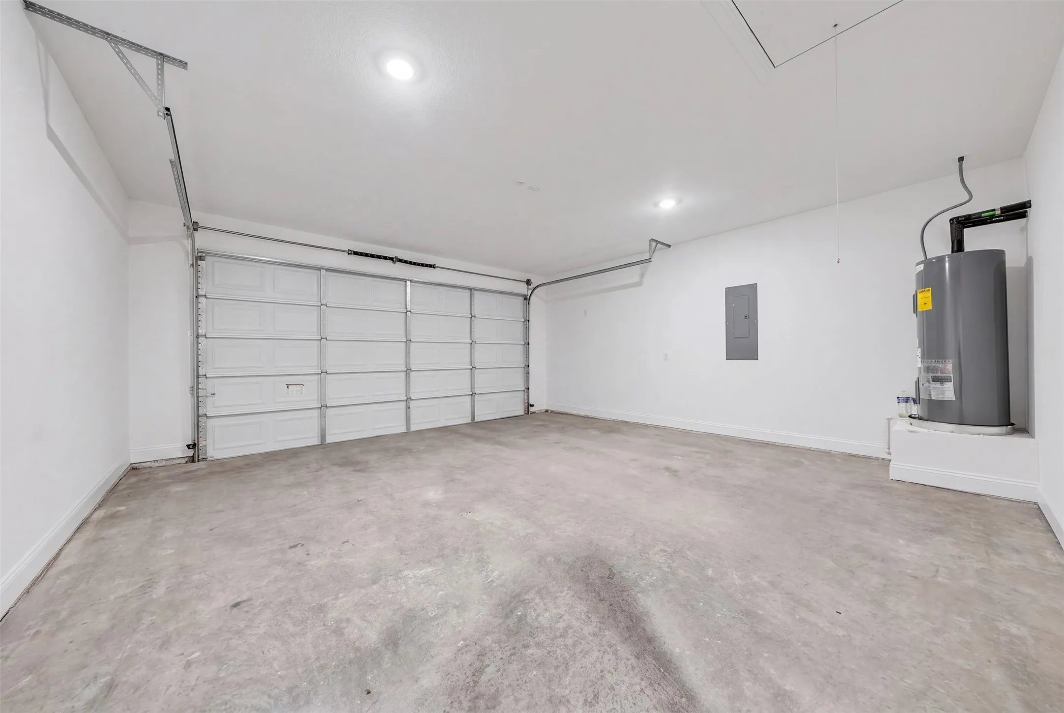 Spacious garage featuring a concrete floor, white panel garage door, recessed lighting, and a utility access panel