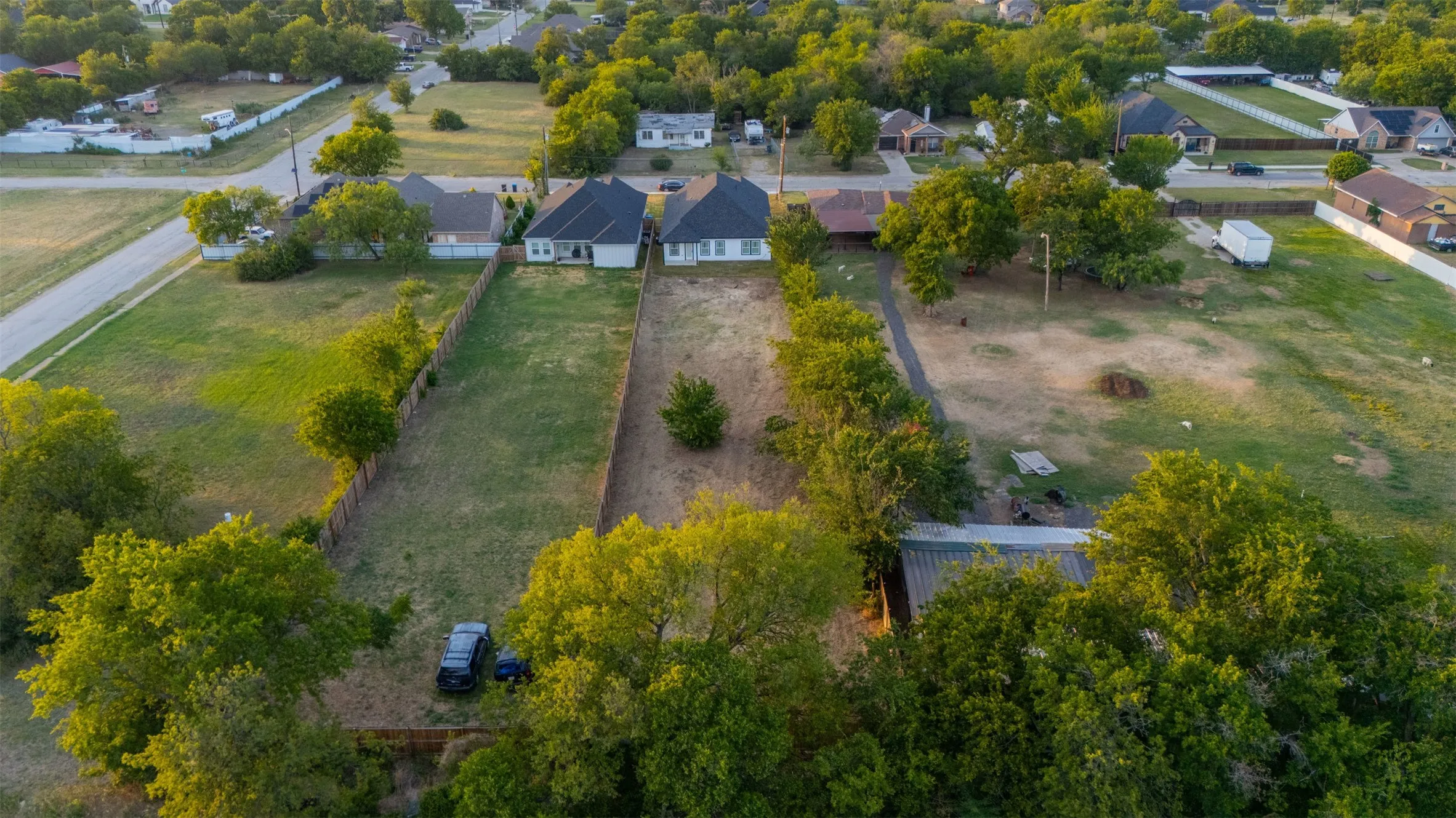 Expansive land parcel featuring mature perimeter trees, a partial fence line, and open grassy areas