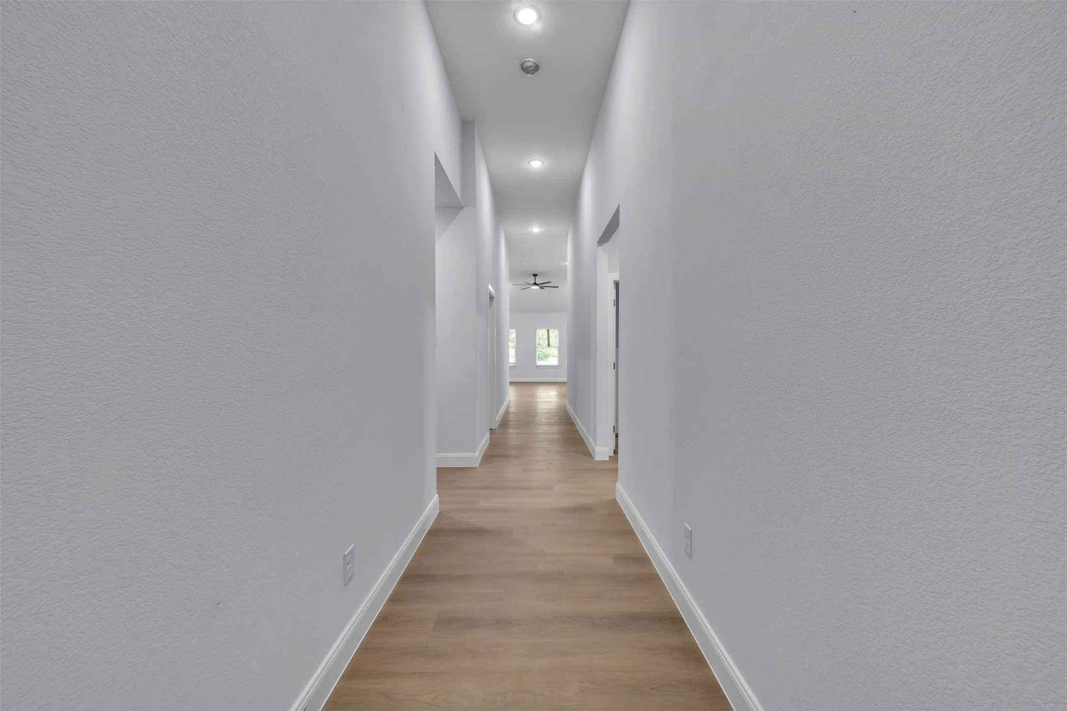 Long hallway featuring wood-finish flooring, recessed lighting, and light gray wall paint