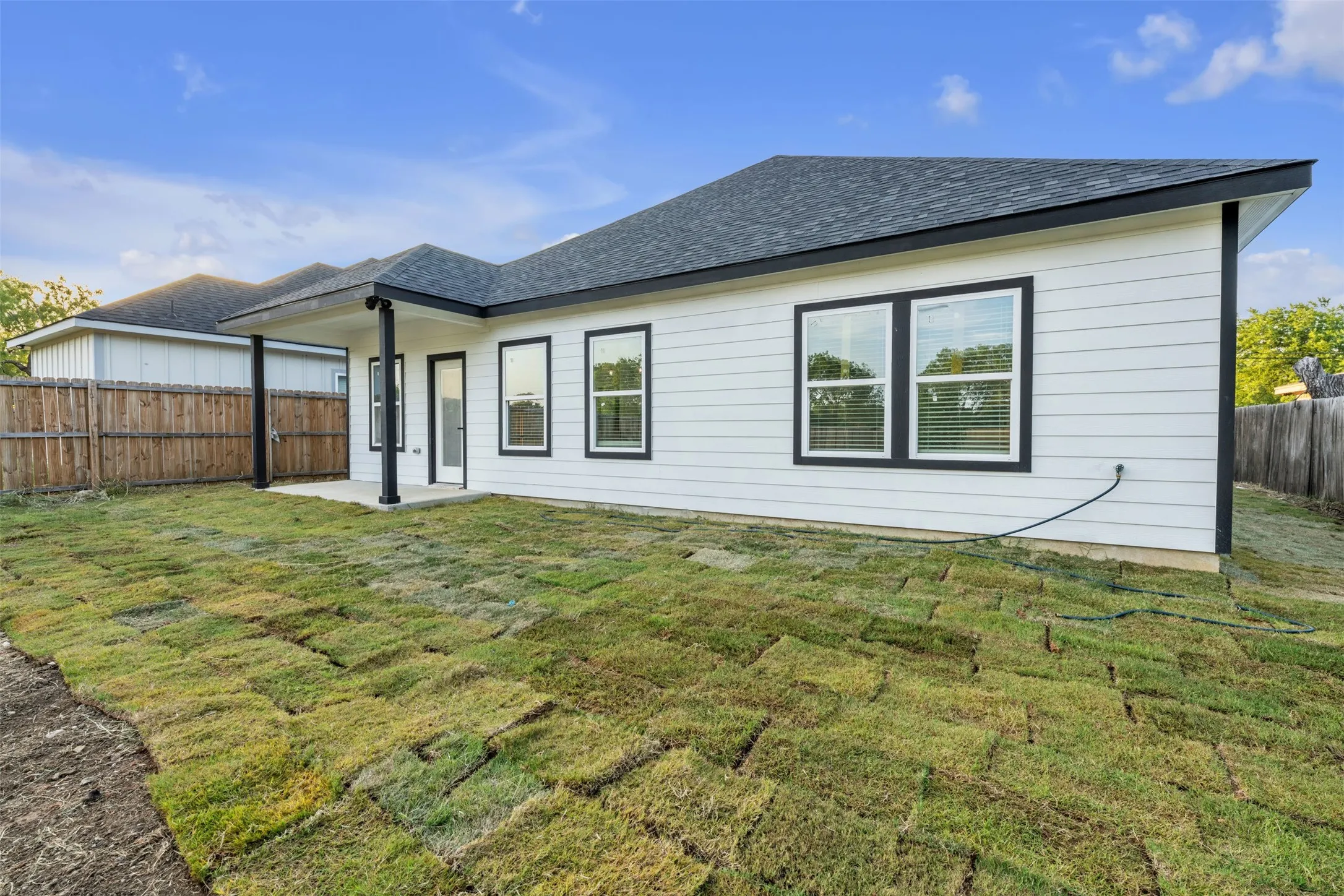 Newly sodded backyard with a covered concrete patio