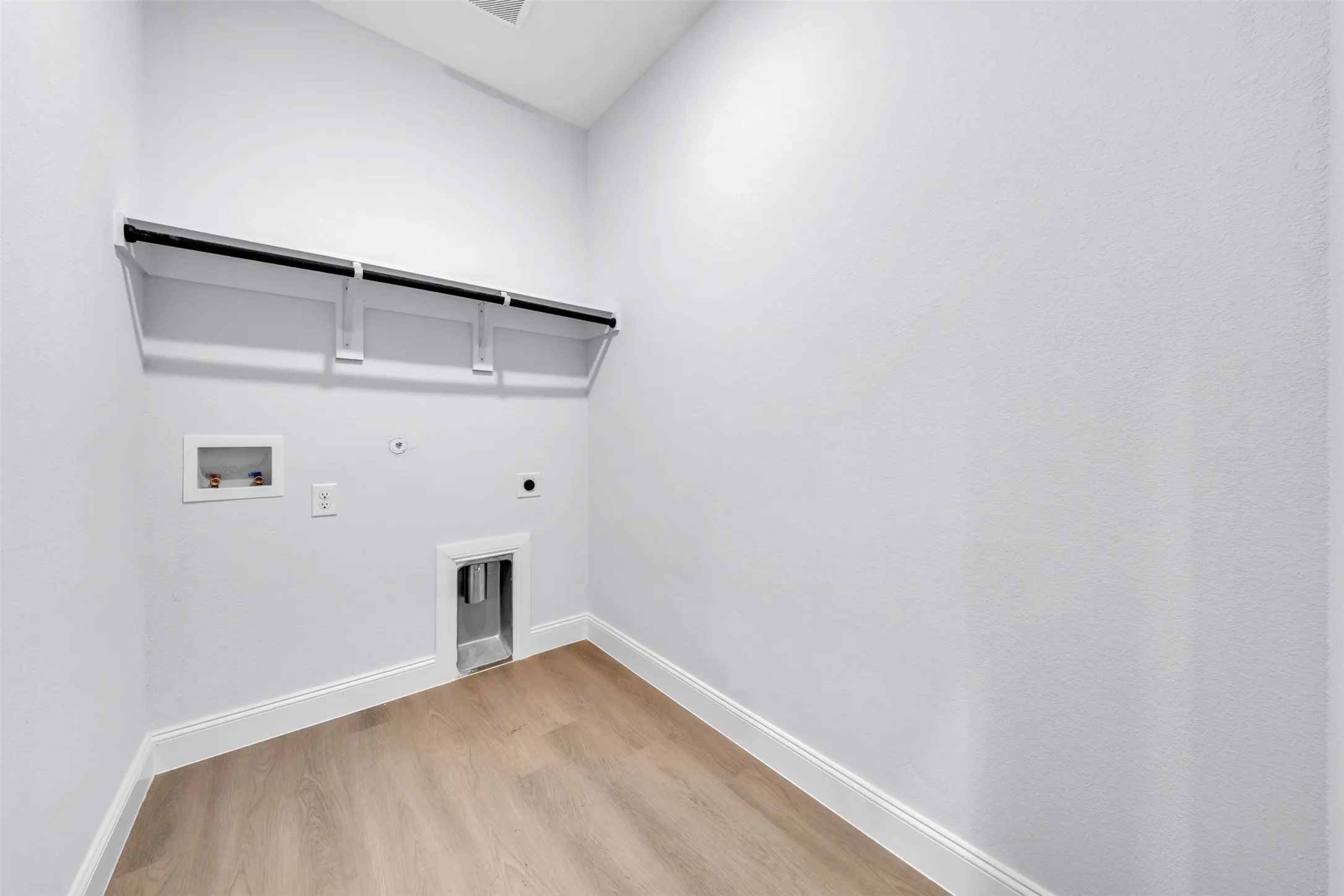 Dedicated utility space featuring light wood-finish flooring and crisp white walls