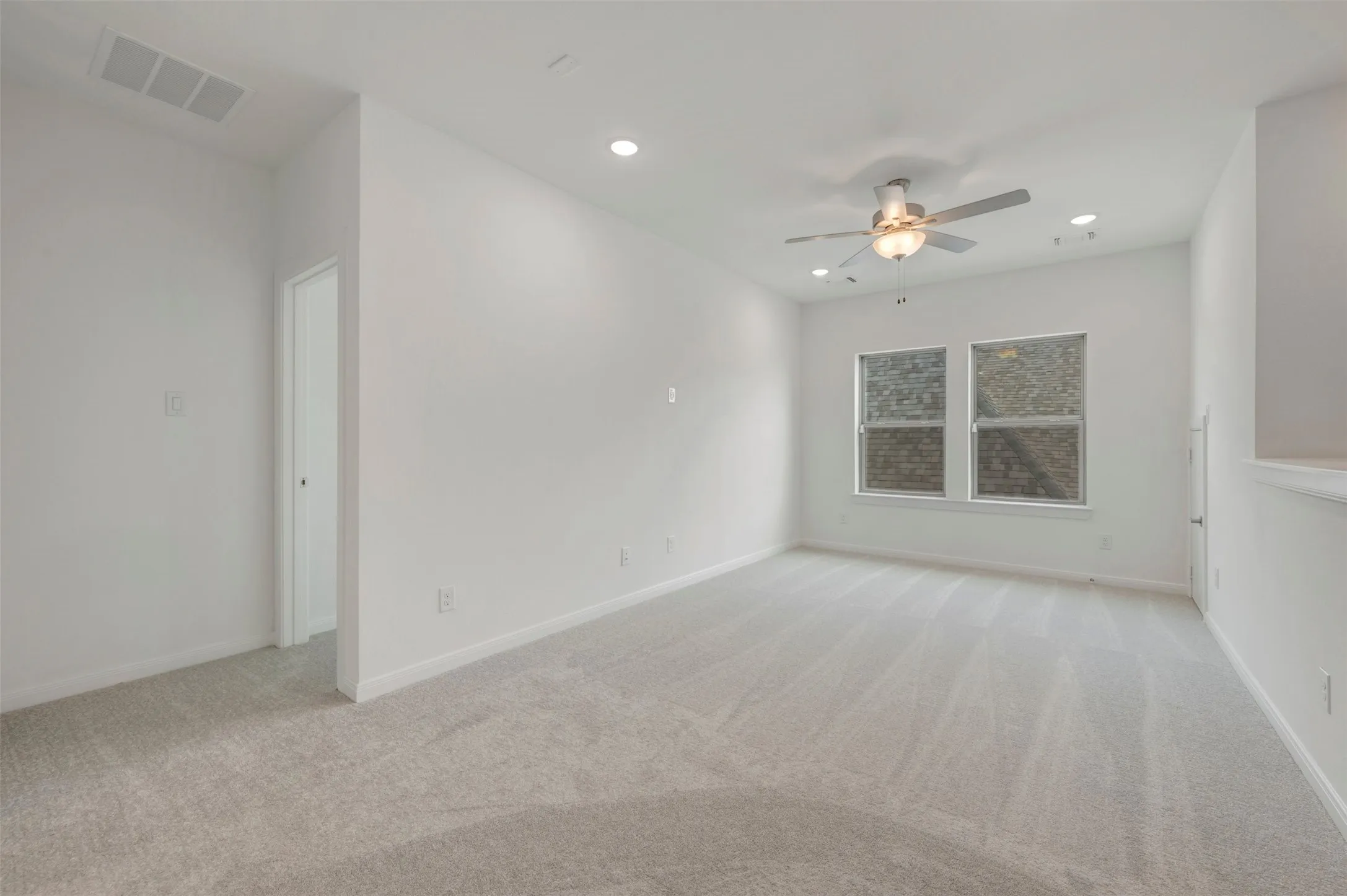 Carpeted room with recessed lighting, a ceiling fan, and two windows