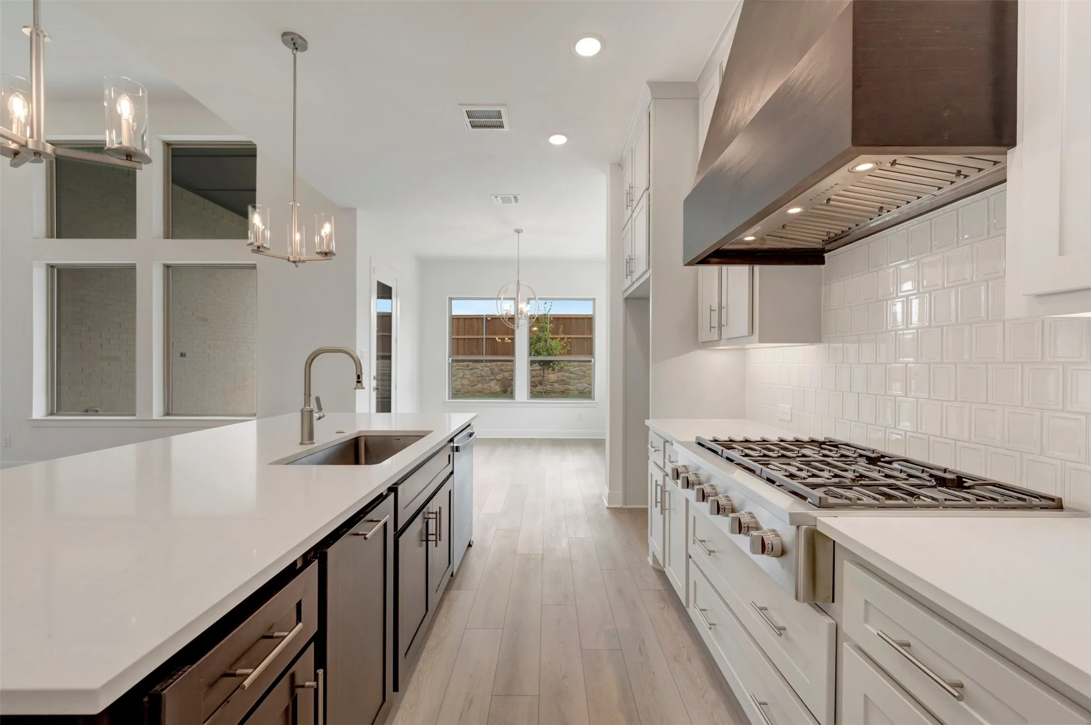 Expansive kitchen island with an undermount sink, white countertops, and dark wood-finish cabinetry