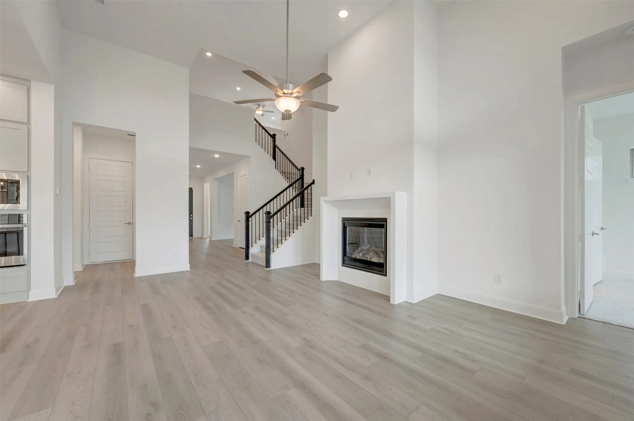 Vaulted ceilings with recessed lighting, wood-finish flooring, and a fireplace with a white surround