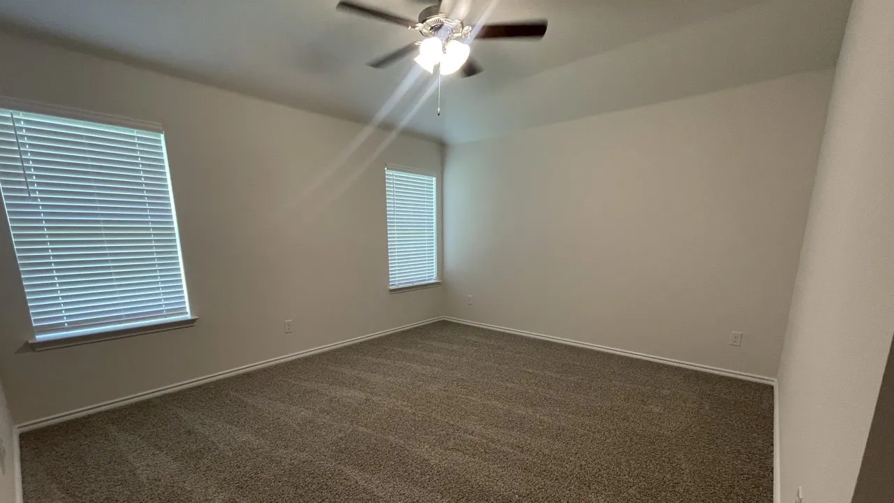 Spacious room featuring neutral carpeting, light-toned walls, and white trim