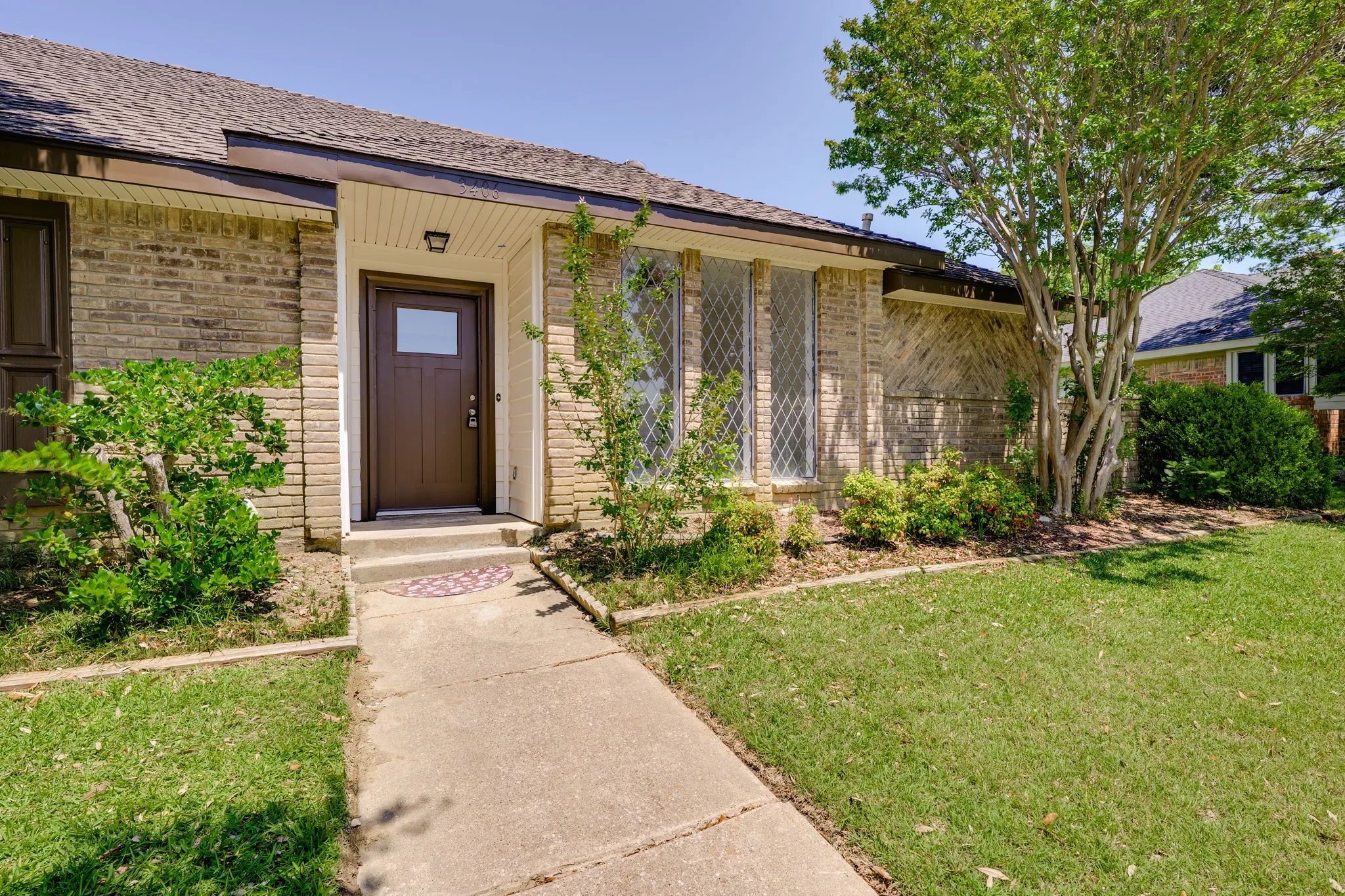 Brick exterior with an entryway featuring a brown door with a window pane