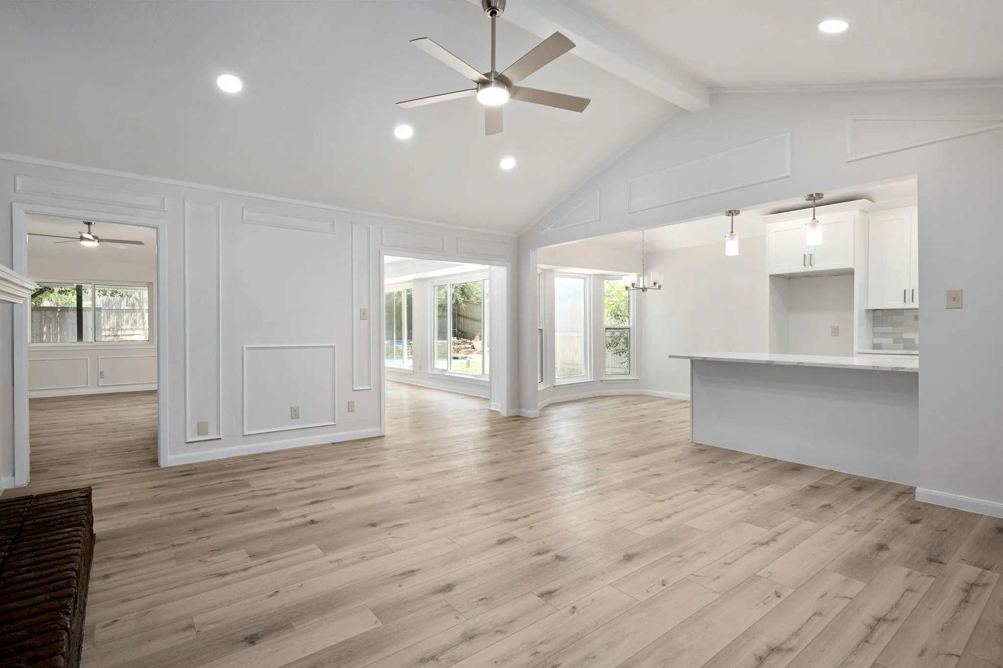 Vaulted ceilings with exposed beams, recessed lighting, and a ceiling fan