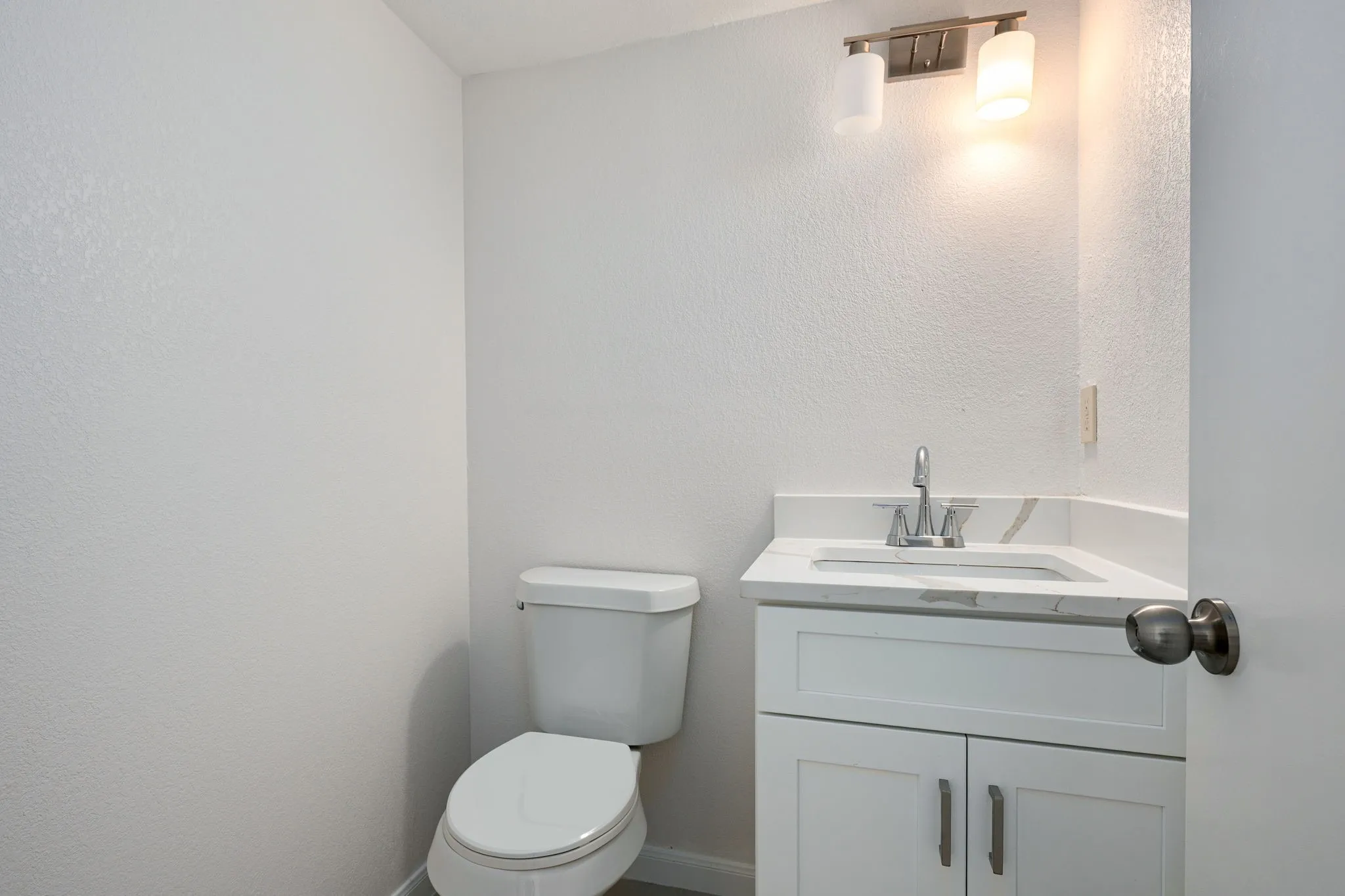 Modern bathroom vanity featuring a white cabinet, integrated sink, and stone-finish countertop