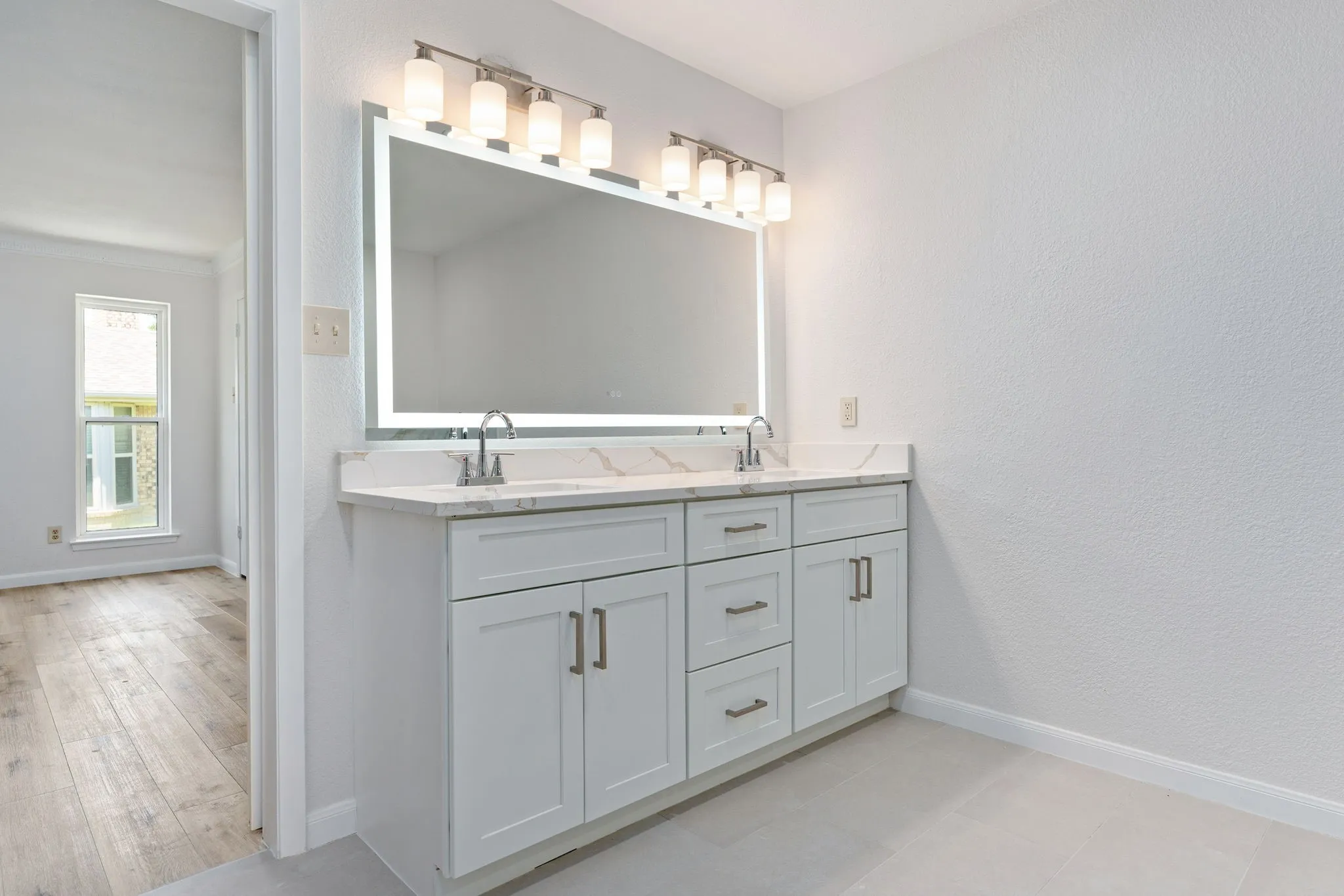 Dual vanity featuring white shaker cabinetry, brushed nickel hardware, and a stone-finish countertop