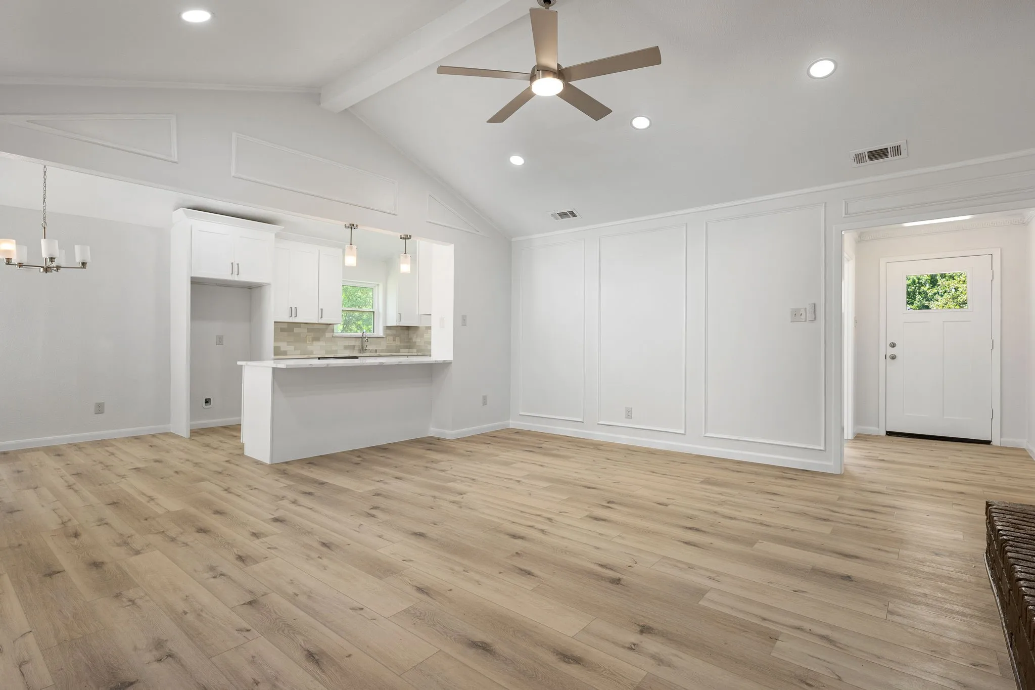 Open-concept living space with vaulted ceilings, wood-finish flooring, and recessed lighting
