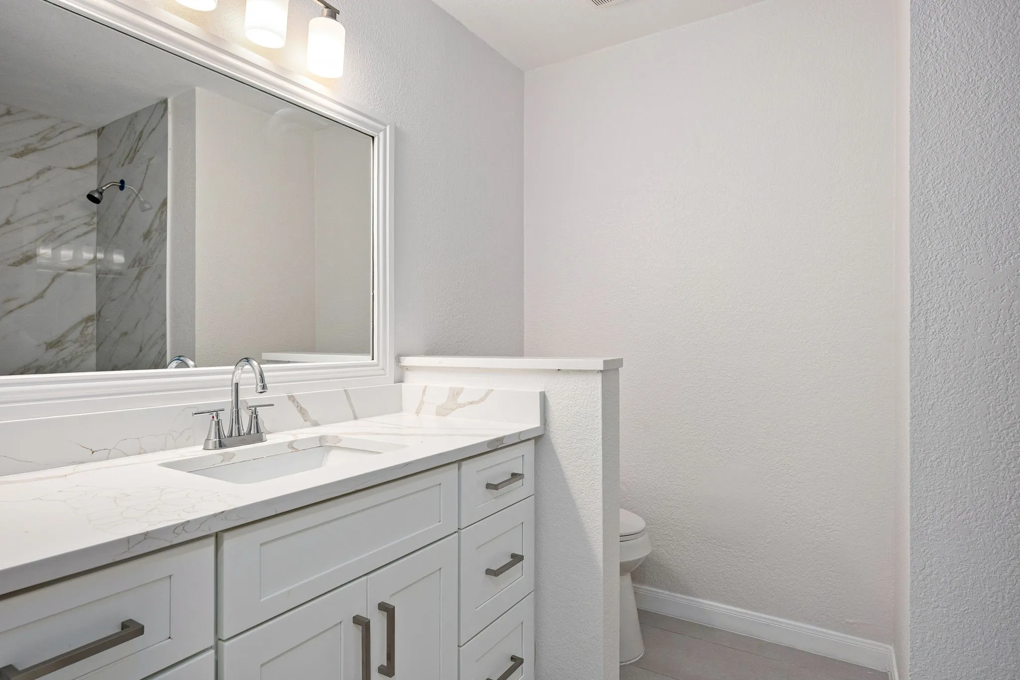 Bathroom vanity featuring a white countertop with integrated sink, brushed nickel faucet, and white cabinetry with coordinating hardware