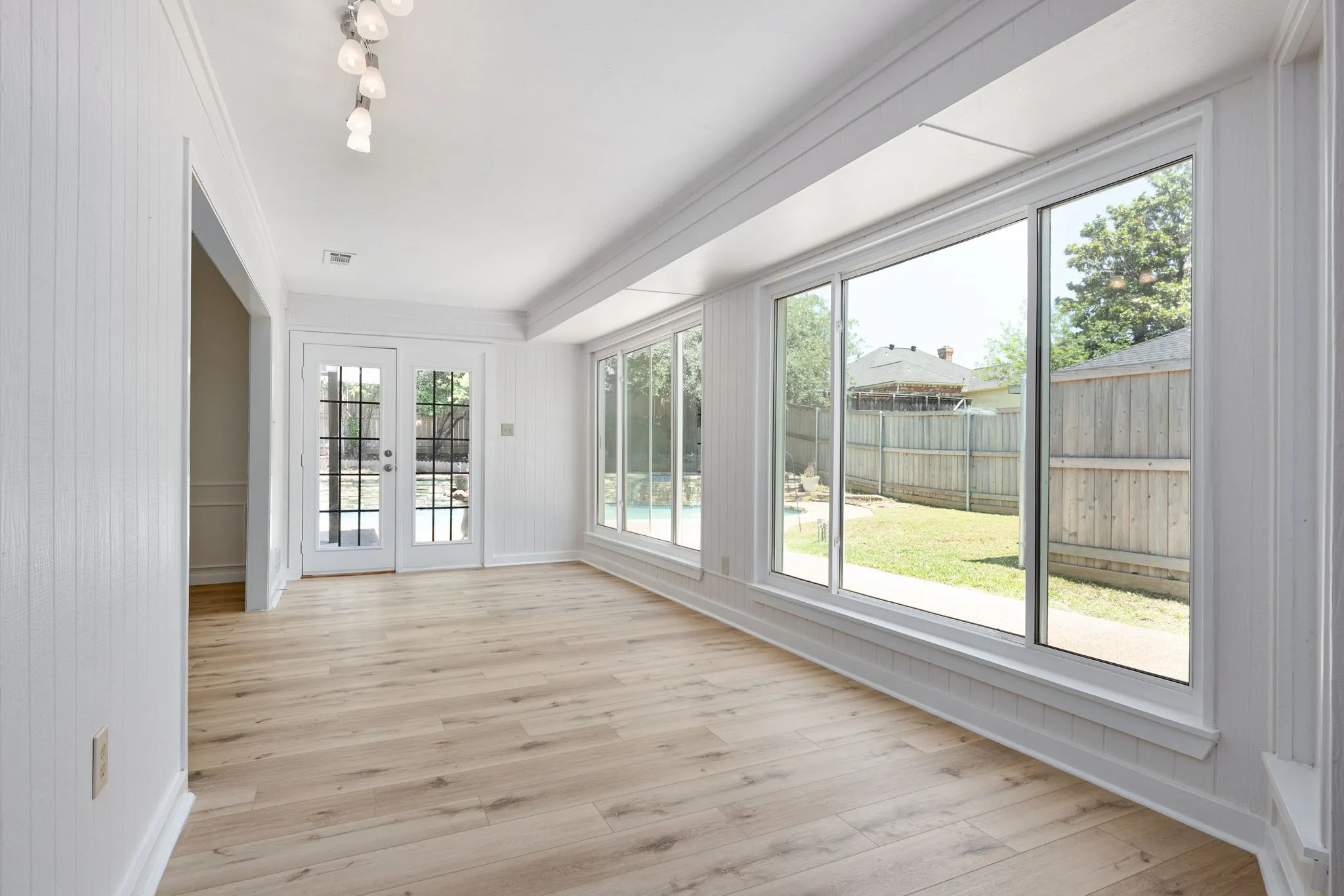 Bright interior space featuring wood-finish flooring, full-height paneling, and an array of large windows
