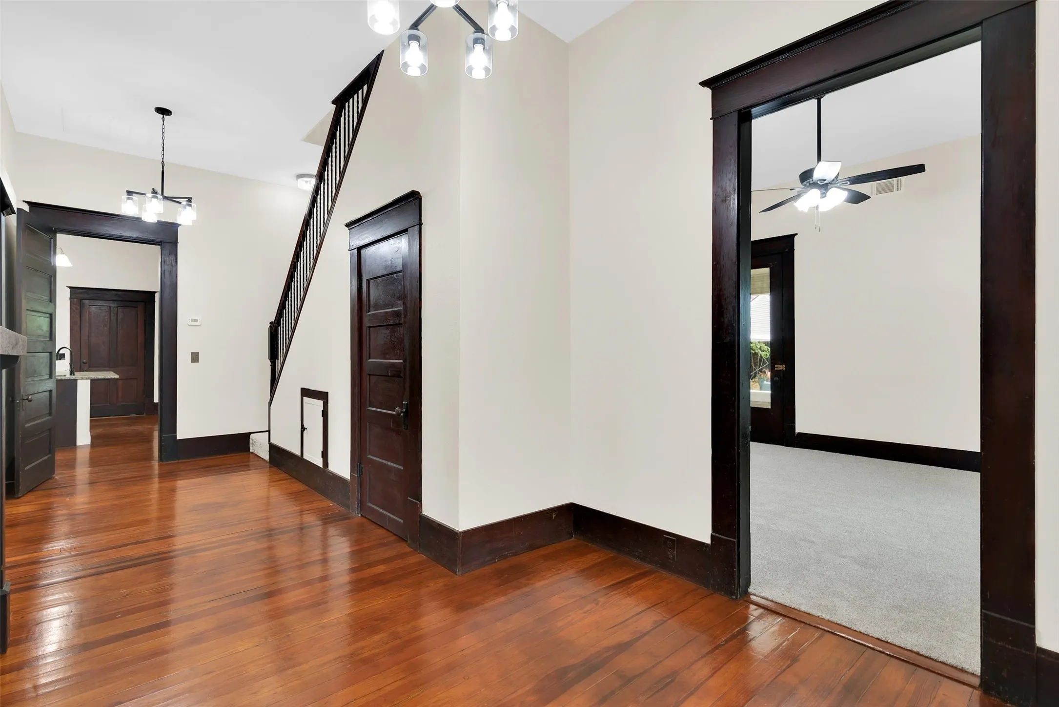 Rich wood flooring extending through the entry hall, staircase with dark wood banister, and dark wood trim throughout