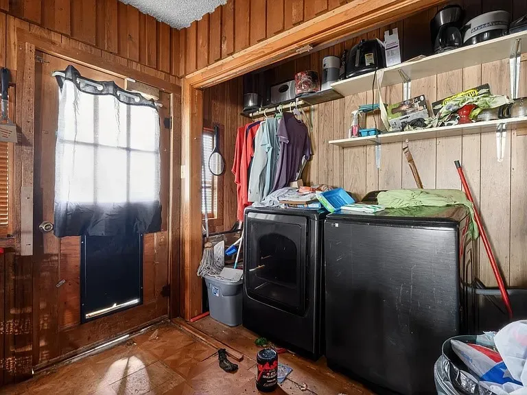 Utility area featuring wood-paneled walls and a door with an integrated pet door