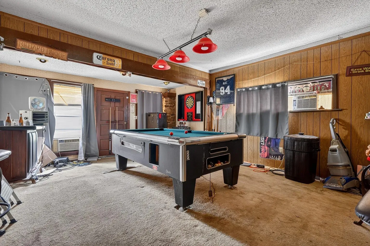 Recreational space featuring wood paneling, a textured ceiling, track lighting with red dome fixtures, and a wood-finish bar area