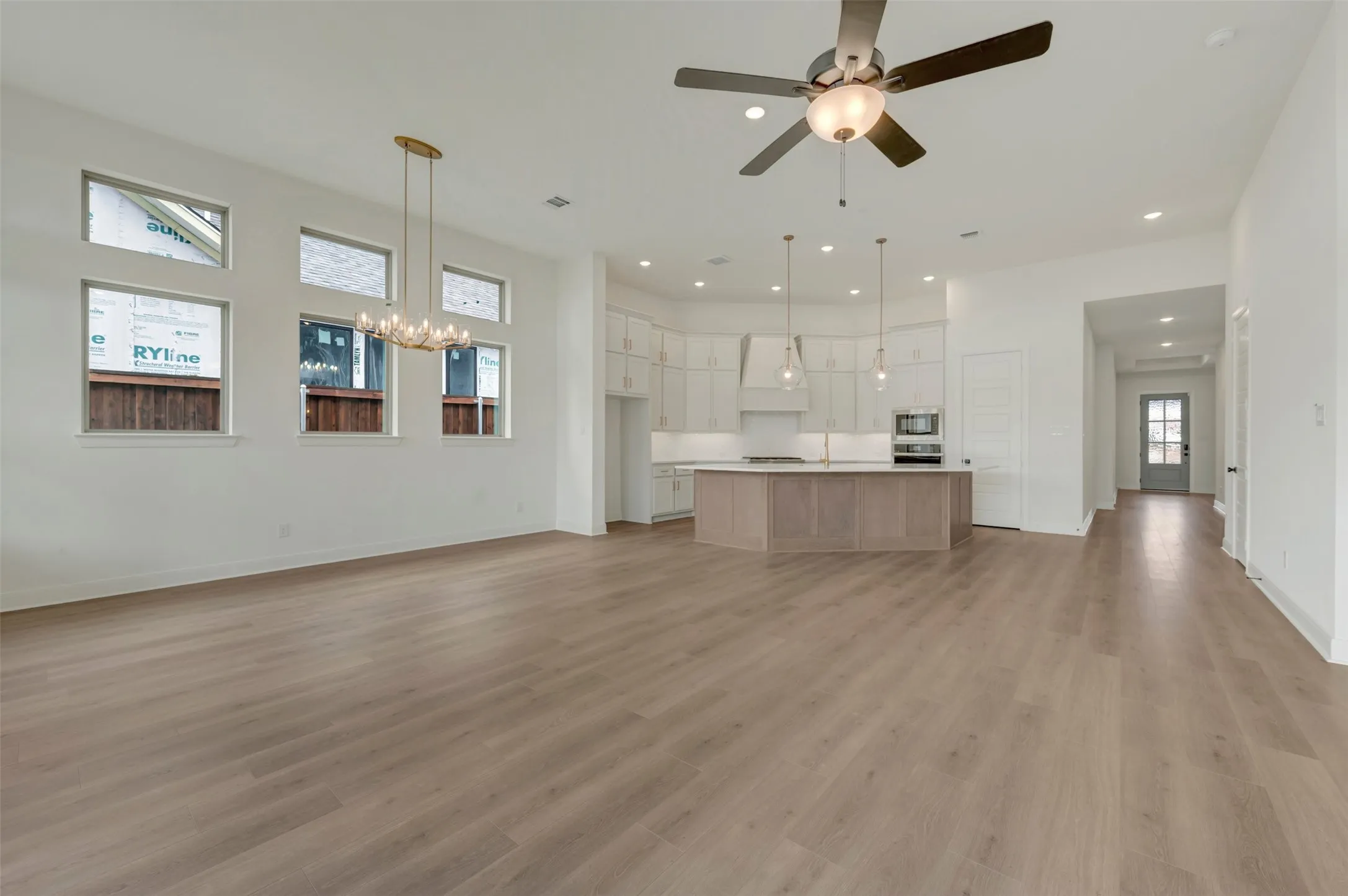 Open-concept living area featuring wide-plank wood-finish flooring throughout, recessed lighting, and a ceiling fan