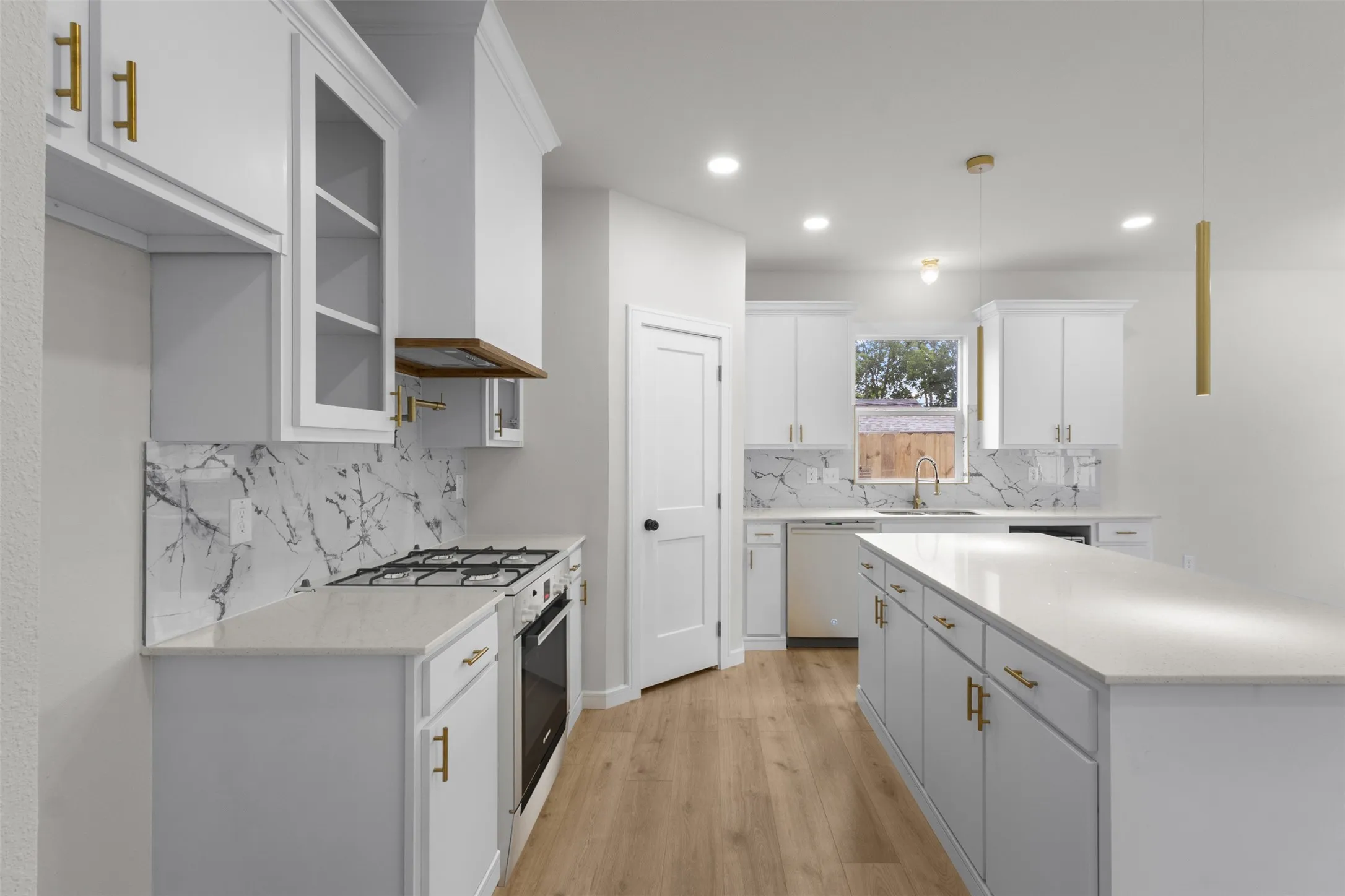 Contemporary kitchen featuring white cabinetry, light countertops, a patterned backsplash, wood-finish flooring, and a central island