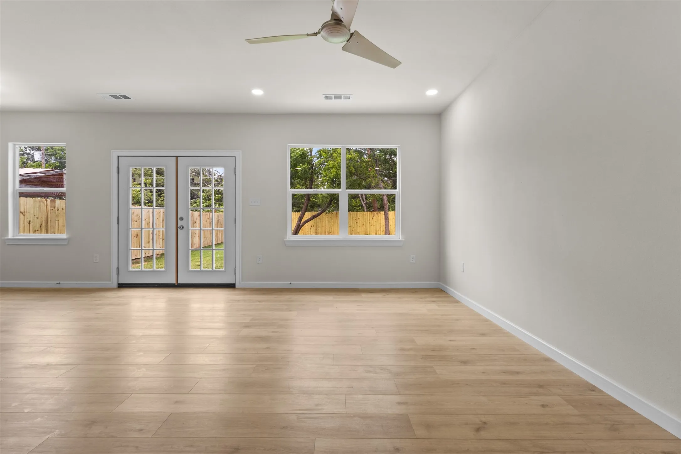 Spacious room featuring wood-finish flooring, recessed lighting, and a modern ceiling fan