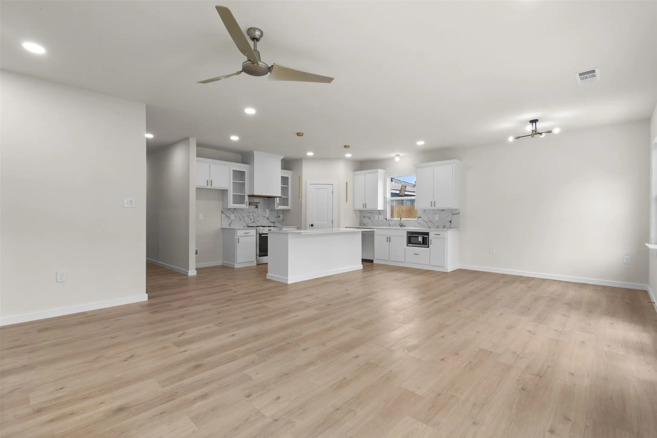 Open-concept living area featuring light wood-finish flooring, recessed lighting, and a contemporary ceiling fan