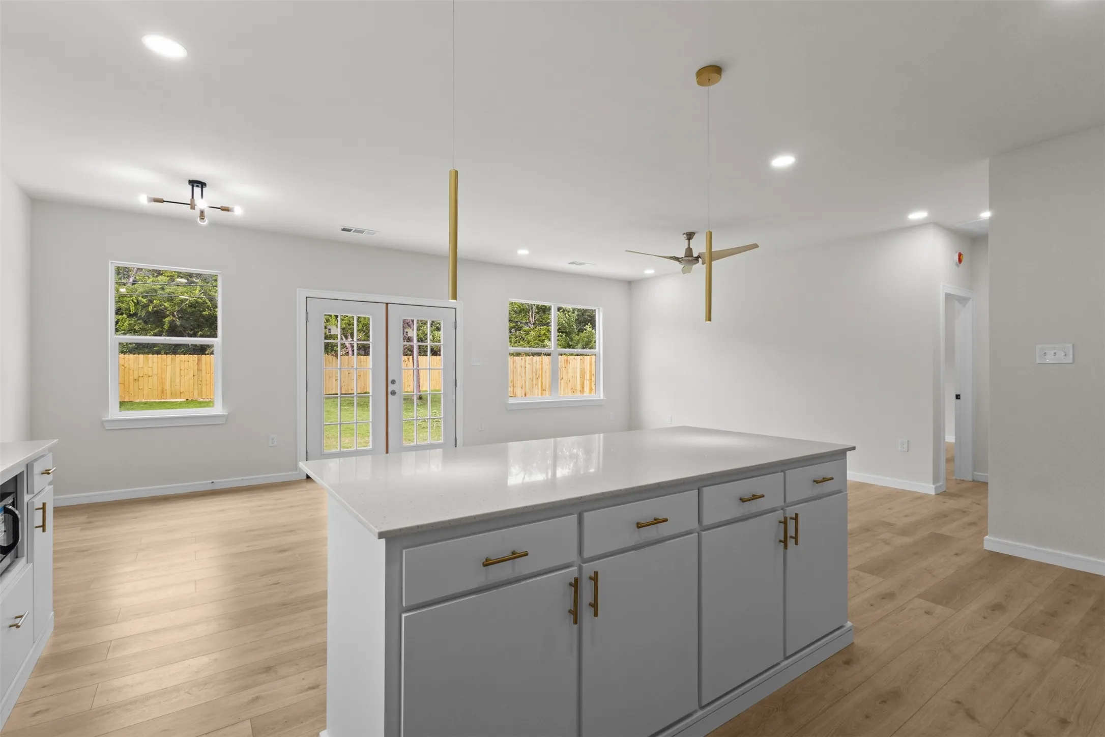 Kitchen island featuring a light-toned countertop, ample storage cabinetry, and gold-finish hardware
