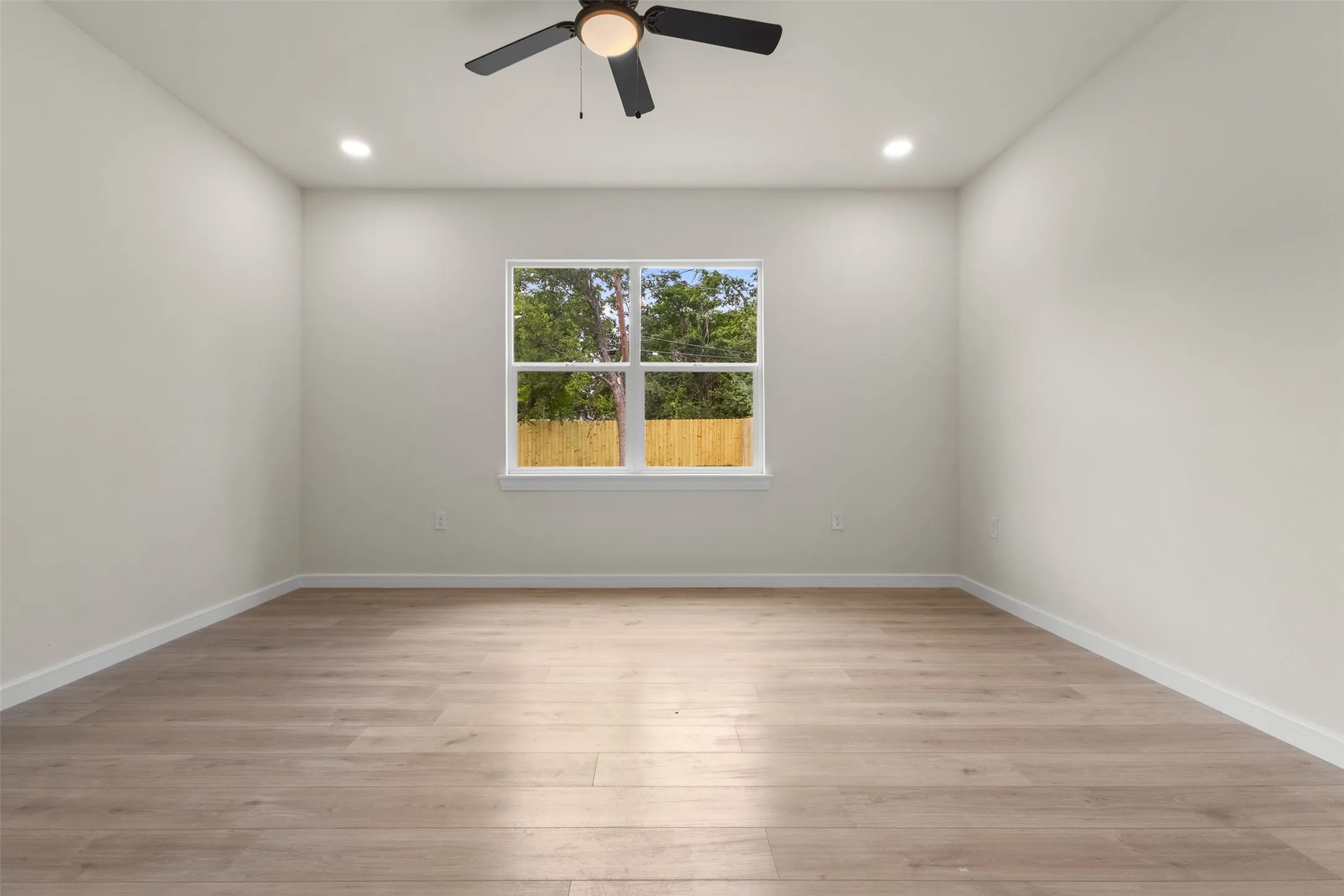 Bright room featuring wood-finish flooring, a ceiling fan with integrated lighting, and recessed ceiling lights