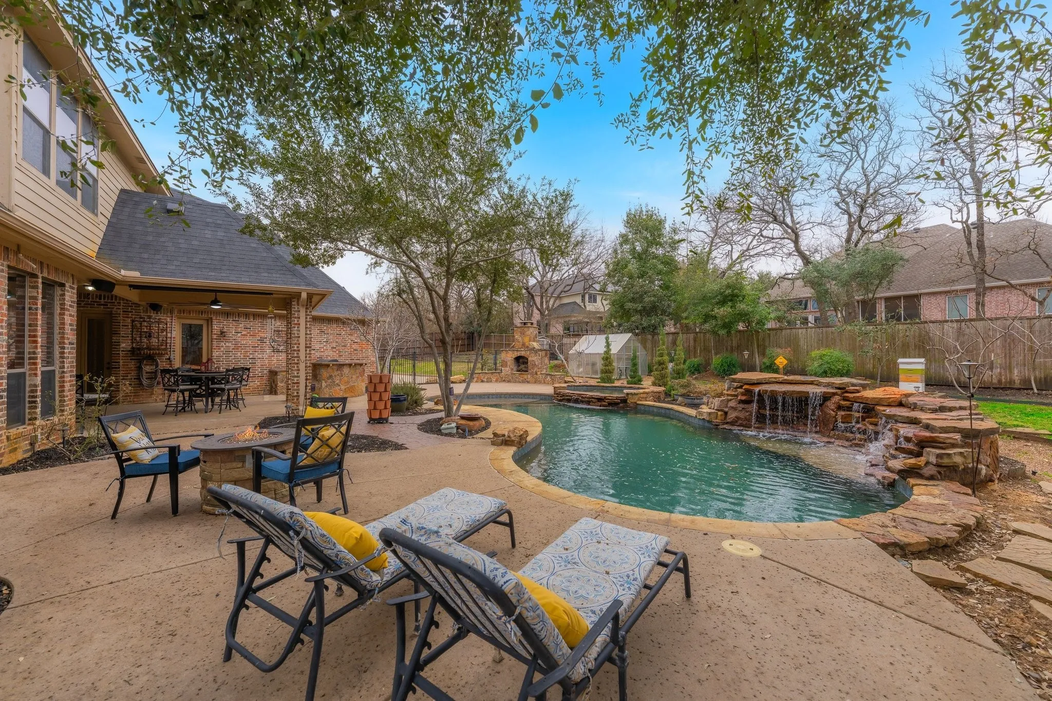 Freeform swimming pool with a rock waterfall feature and surrounding stone hardscaping