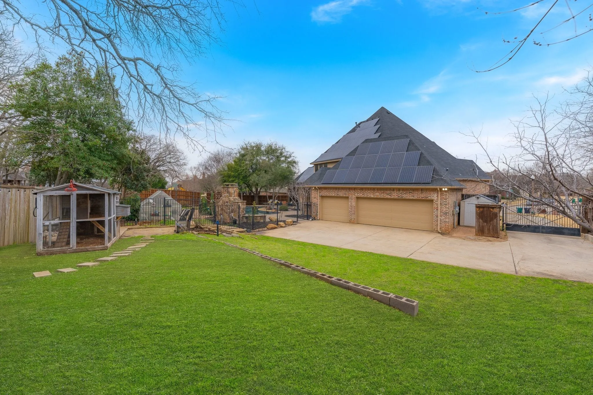 Expansive backyard featuring a green lawn, stepping stone path, and a wooden coop structure