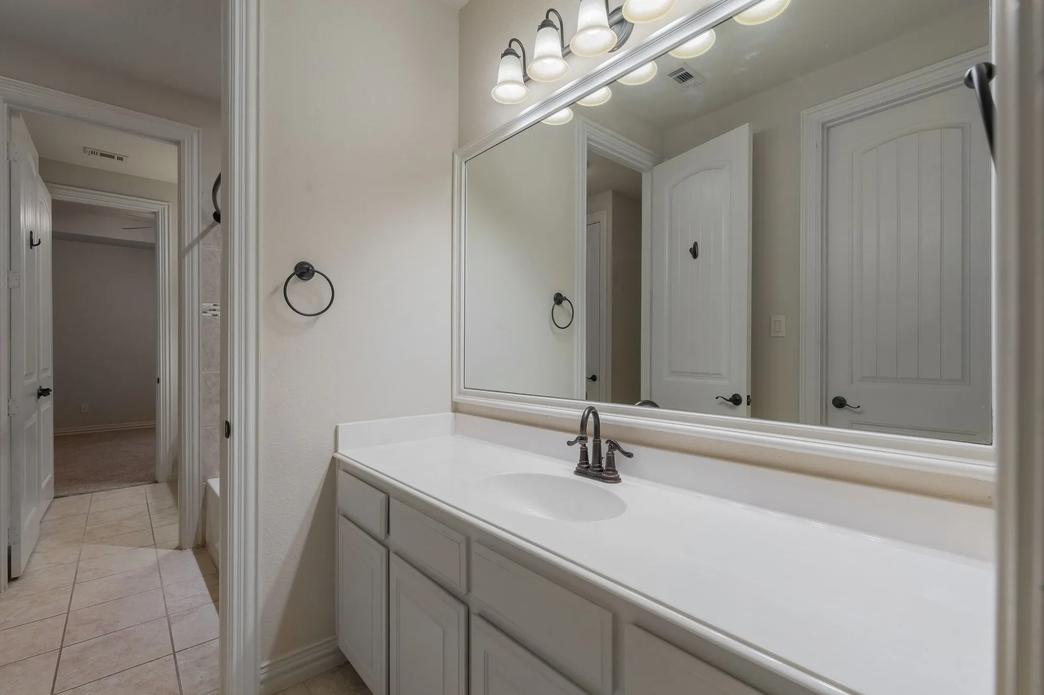 Bathroom vanity with an integrated sink, broad mirror, and a bronze-finish faucet