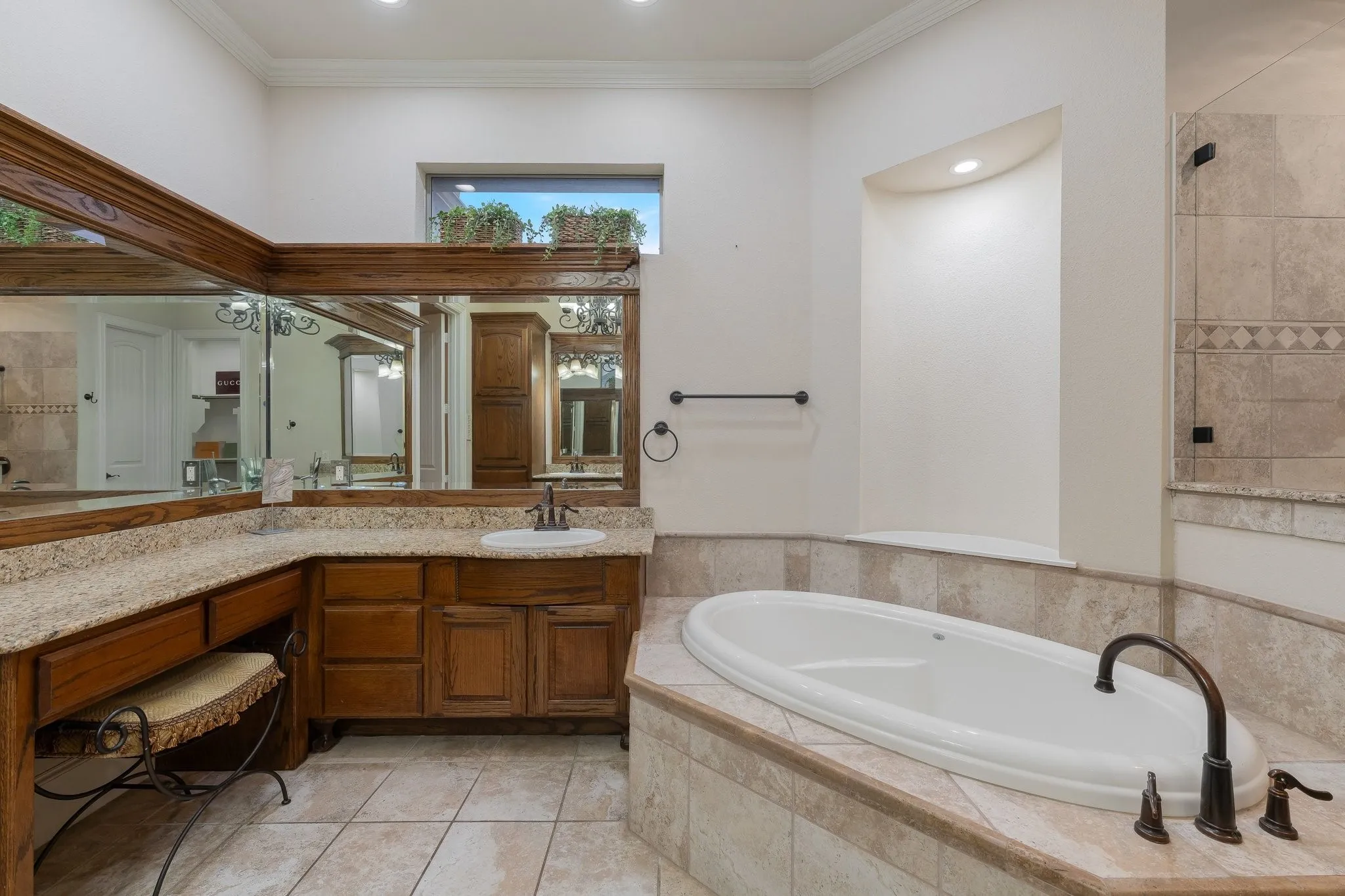 Soaking tub with bronze-finish fixtures, surrounded by stone-look tile