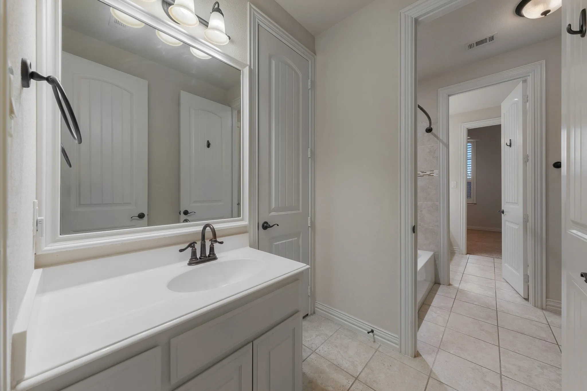 Bathroom vanity with an integrated sink, bronze-finish faucet, and overhead bar lighting