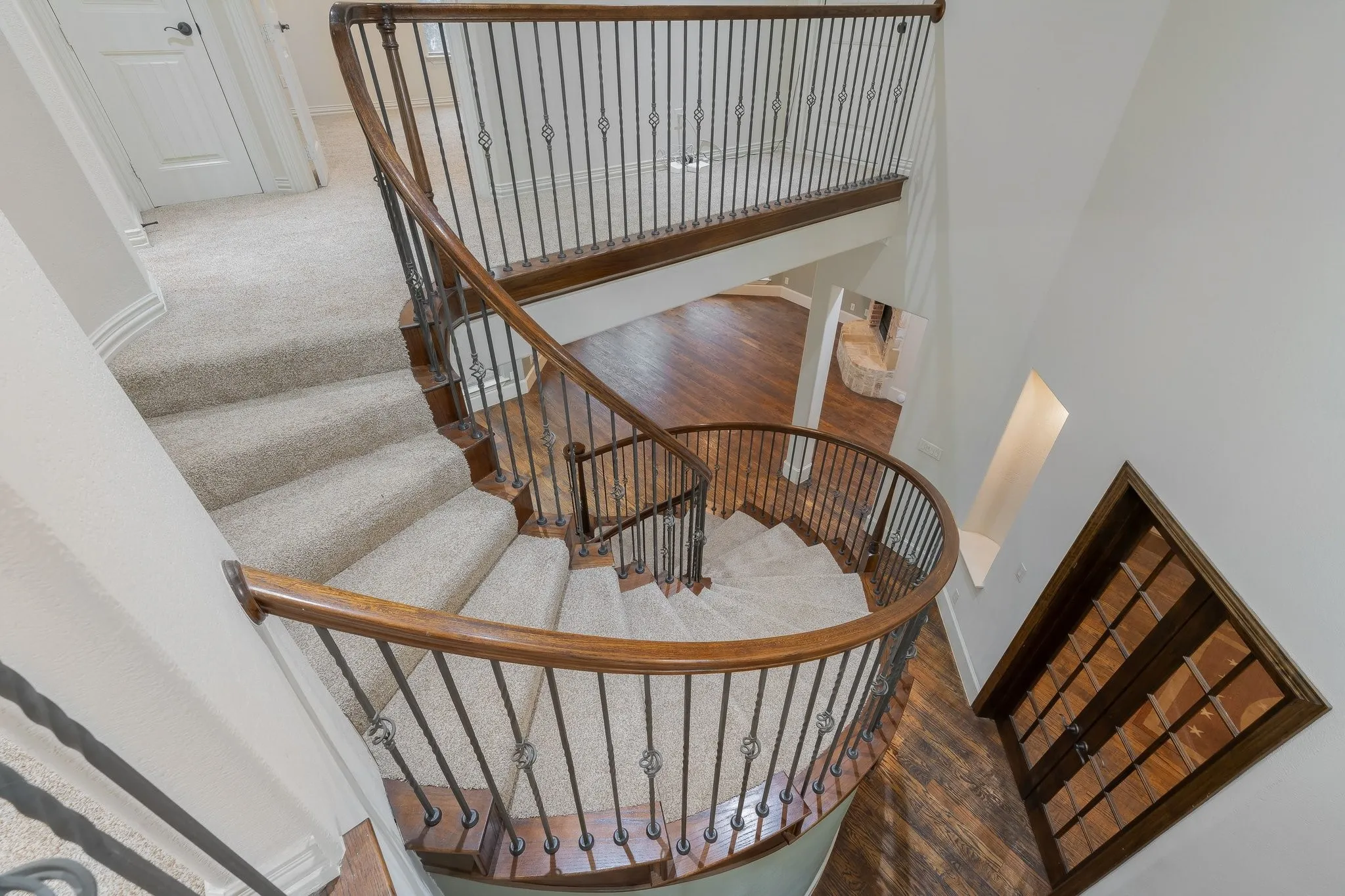 Curved staircase with wood-finish handrails and wrought iron balusters