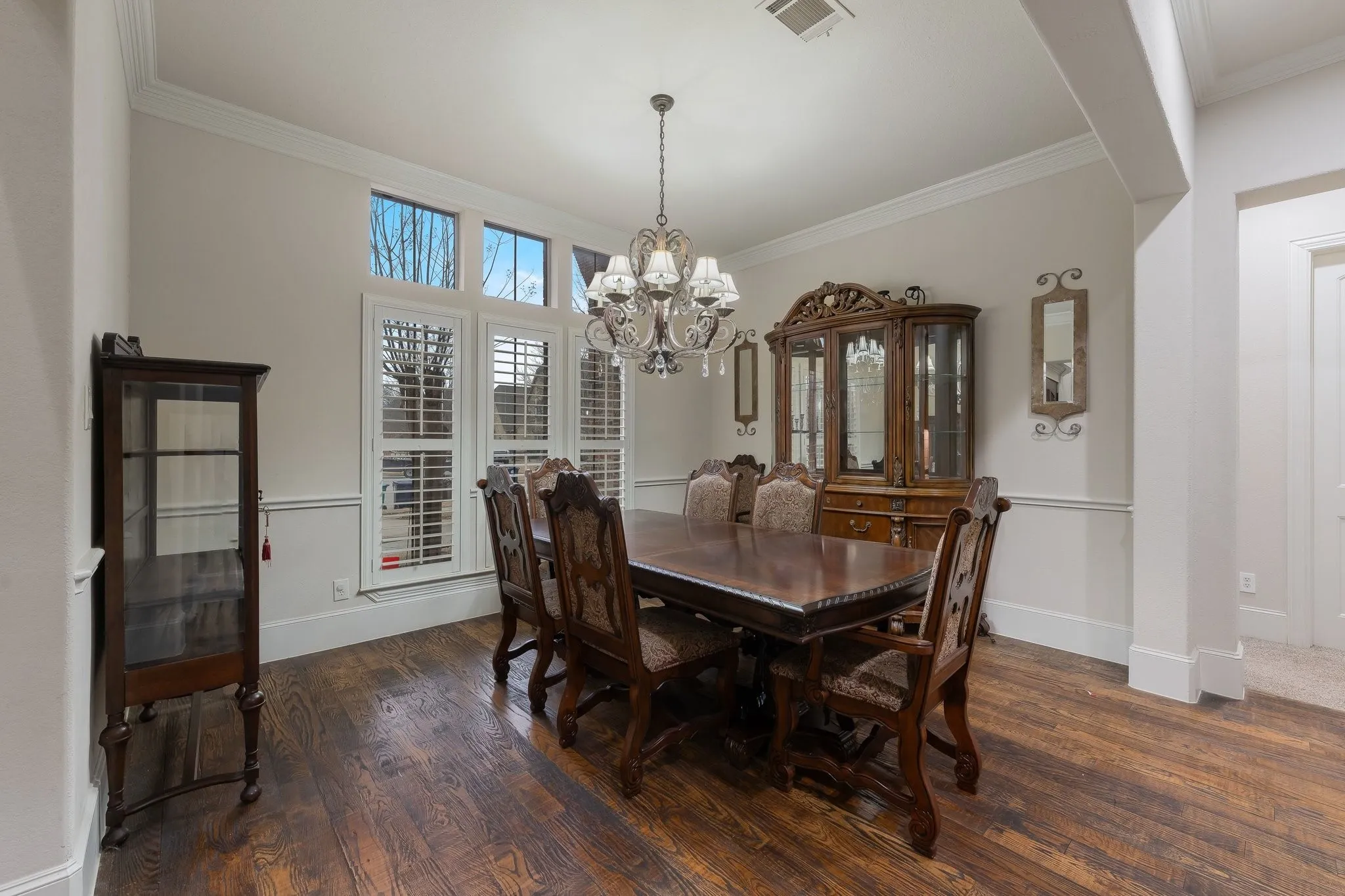 Formal dining space featuring wood-finish flooring, white crown molding, and a crystal chandelier