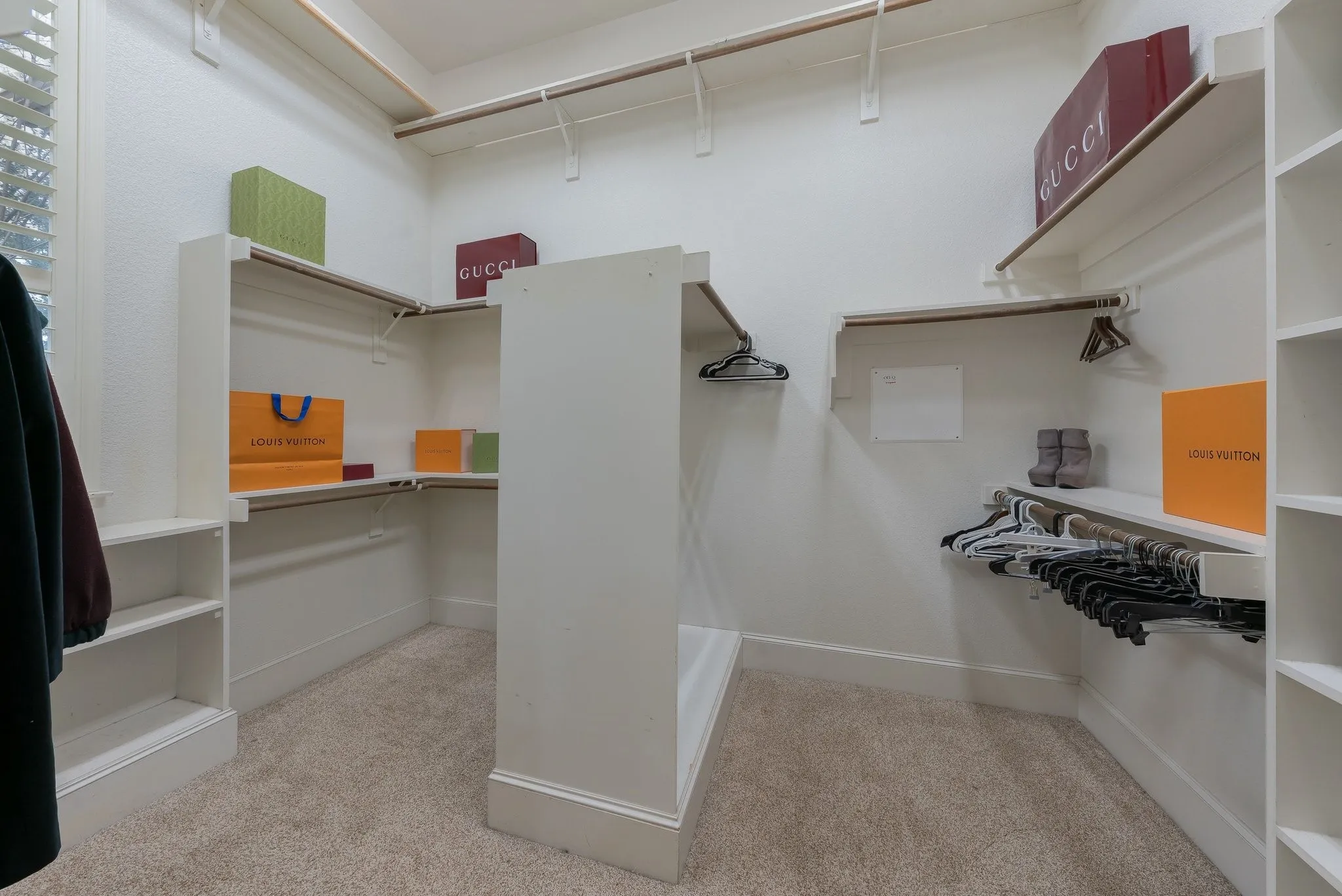 Spacious walk-in closet featuring light-toned carpeting, white shelving, and multiple clothing rods
