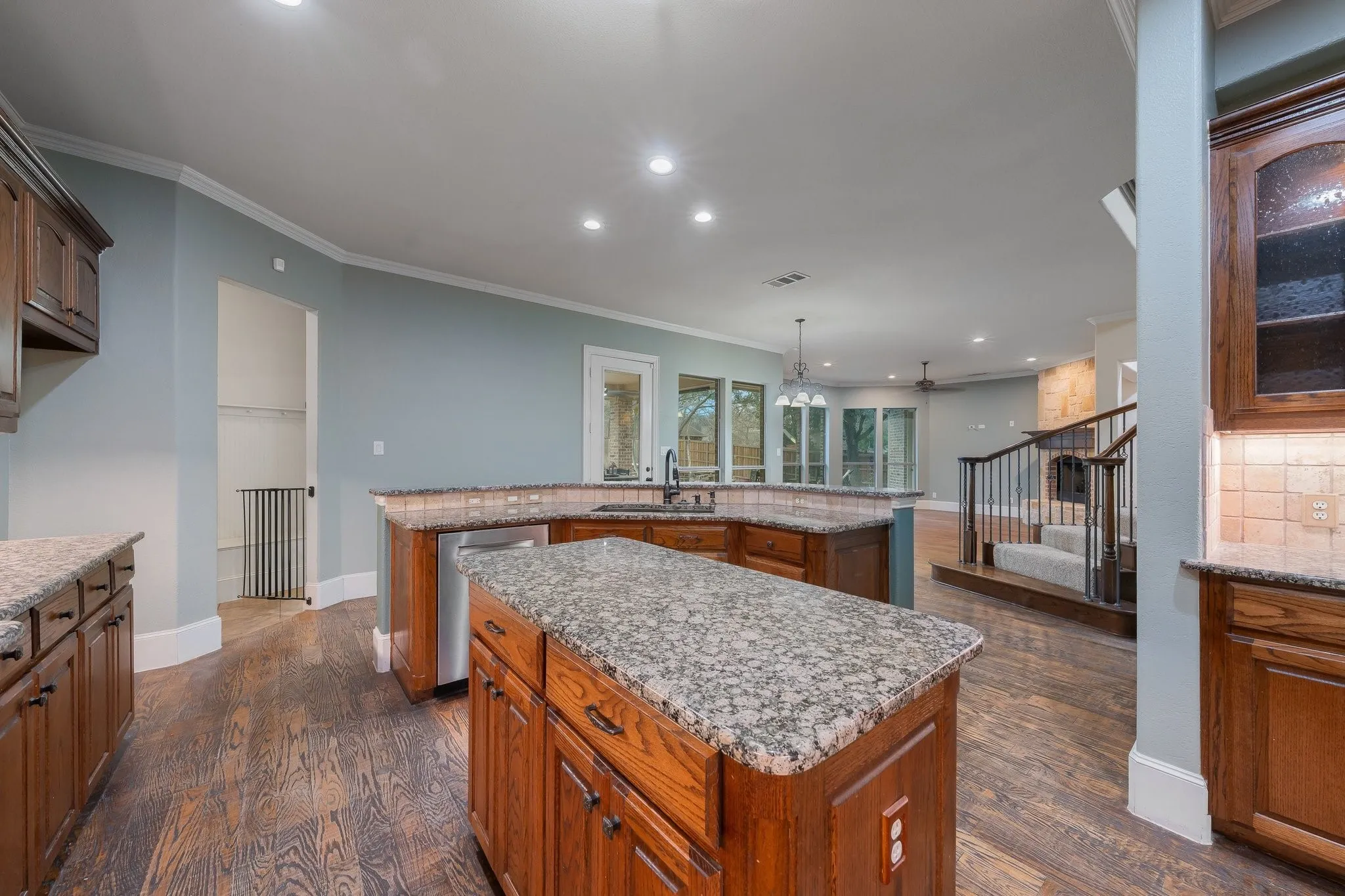 Kitchen featuring a central island with granite countertops, wood-finish flooring, recessed lighting, and rich wood cabinetry