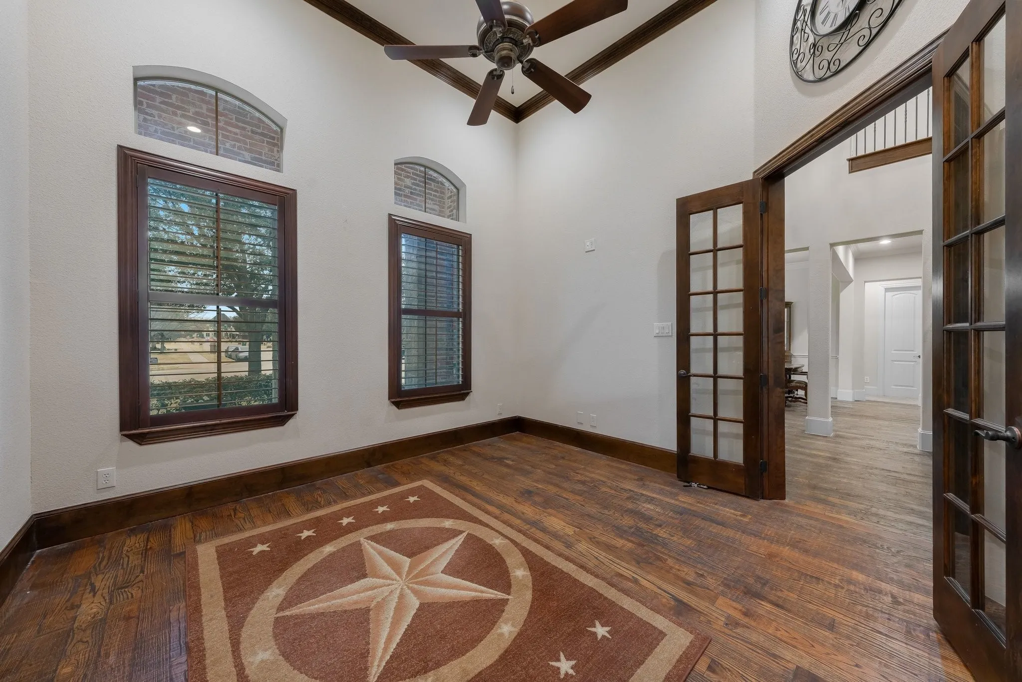 Room featuring wood-finish flooring, dark wood trim, and high ceilings with exposed wood beams