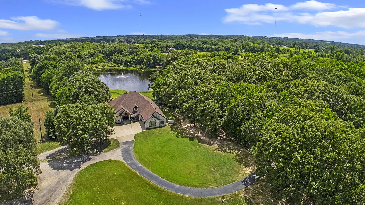 Expansive property featuring a residence with a brown shingle roof and light-toned stone