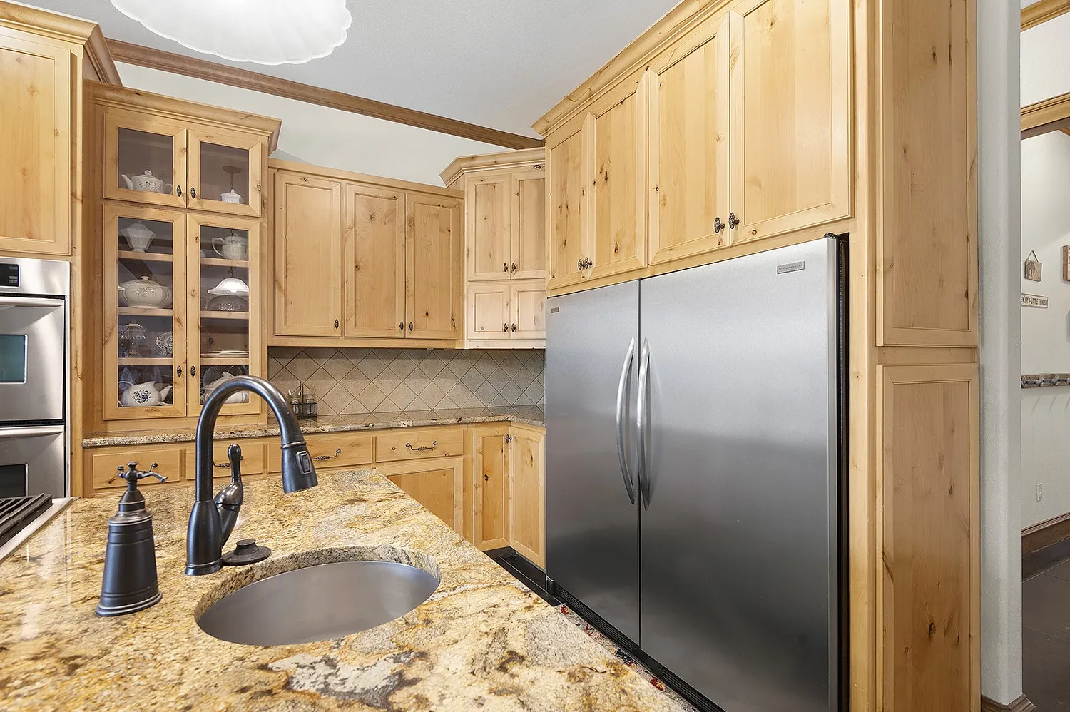 Kitchen featuring wood cabinetry, stainless steel appliances, a built-in double oven, and granite countertops