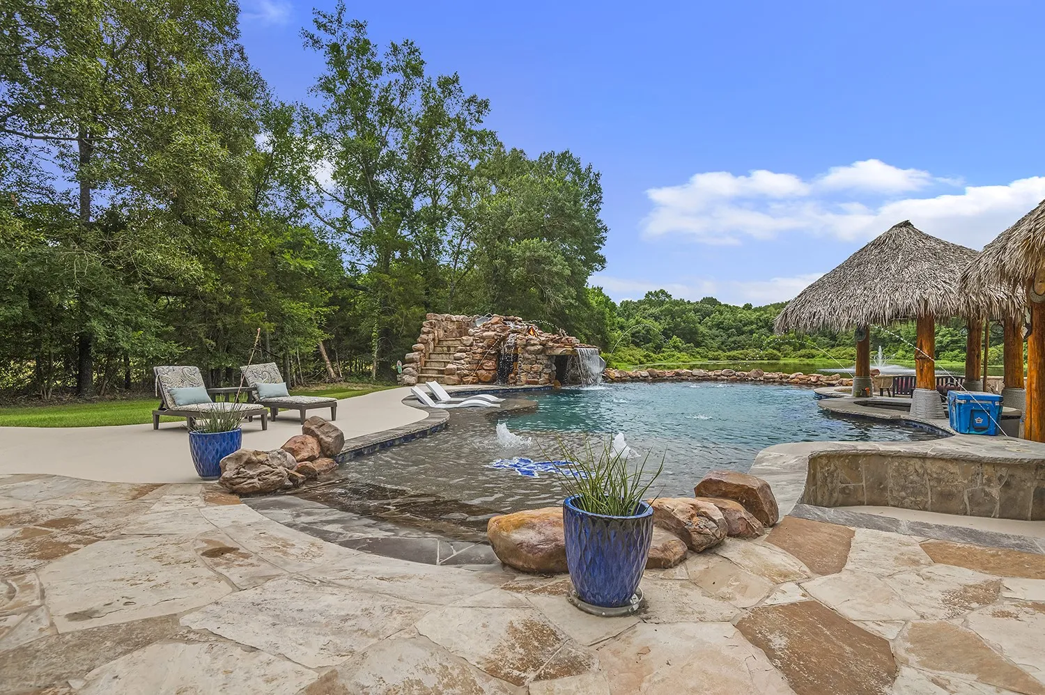 Expansive flagstone patio surrounding a custom swimming pool with a rock waterfall feature