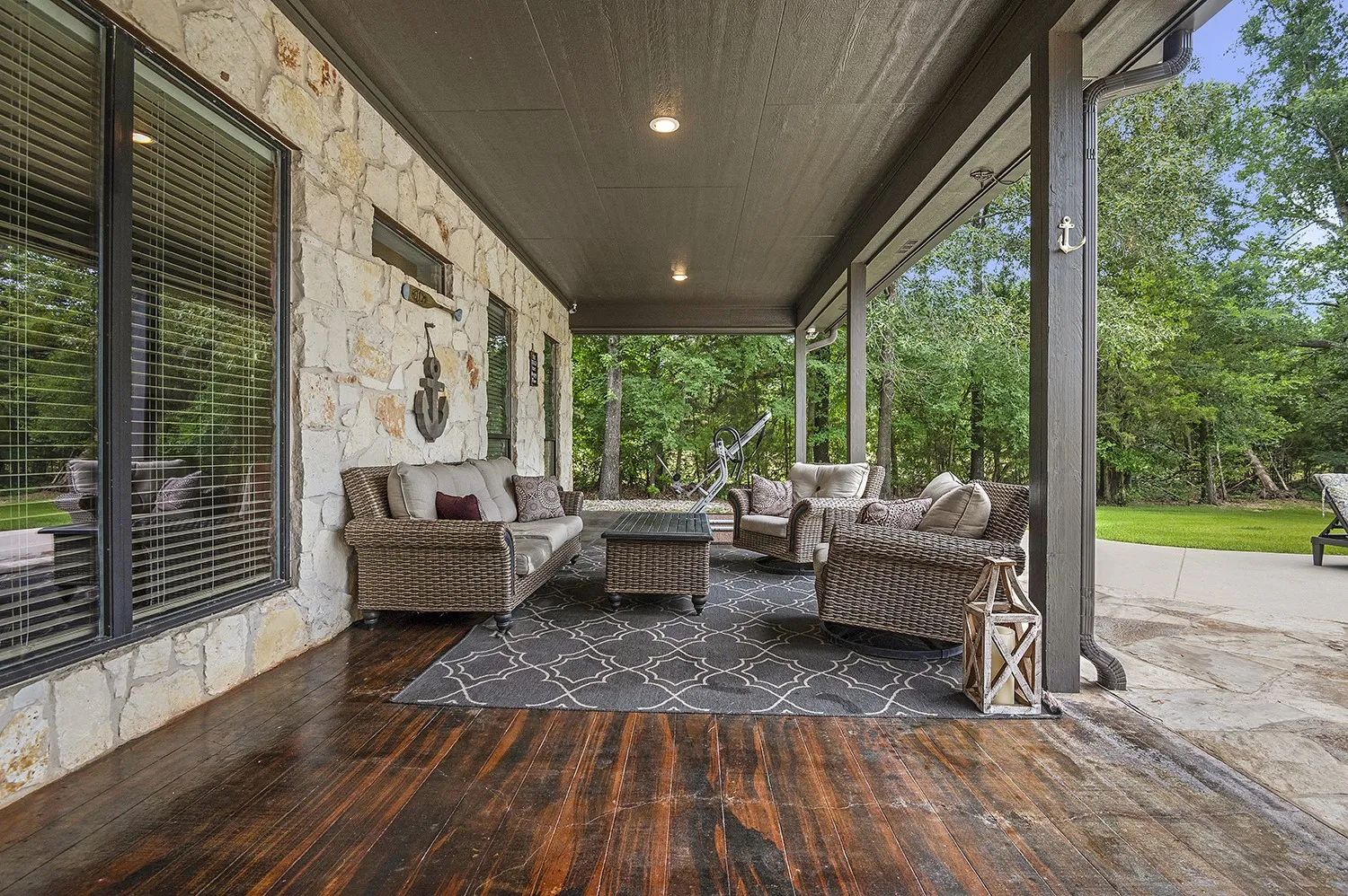 Covered outdoor patio featuring stone veneer exterior, dark wood-finish flooring, and recessed lighting