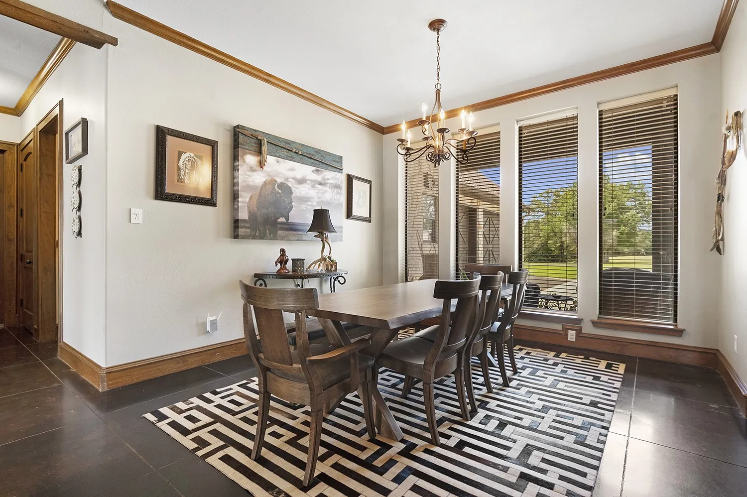 Dining area with dark flooring, contrasting wood-finish trim, and three tall windows