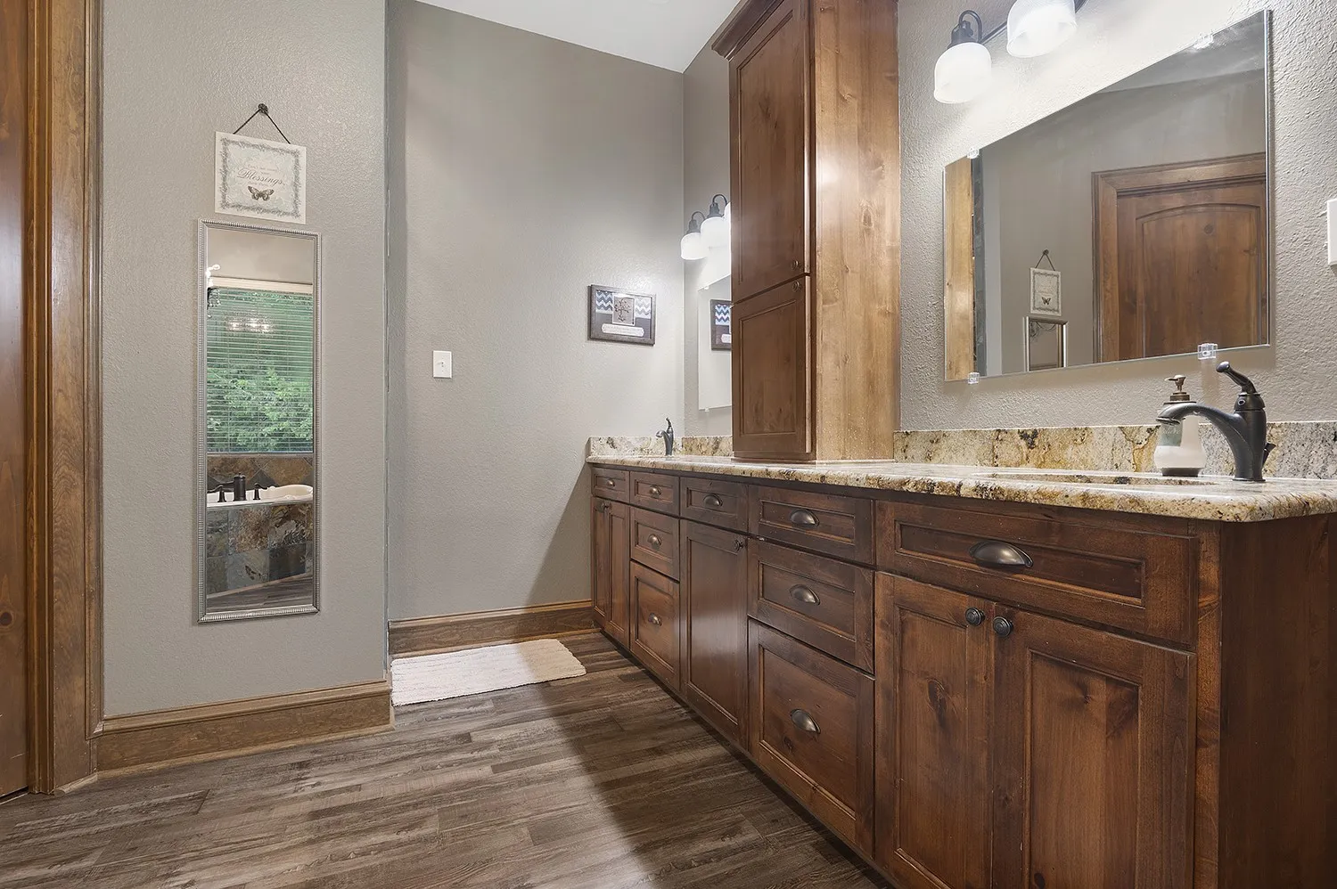 Bathroom featuring dual wood cabinetry vanities with stone countertops, undermount sinks, and dark bronze fixtures