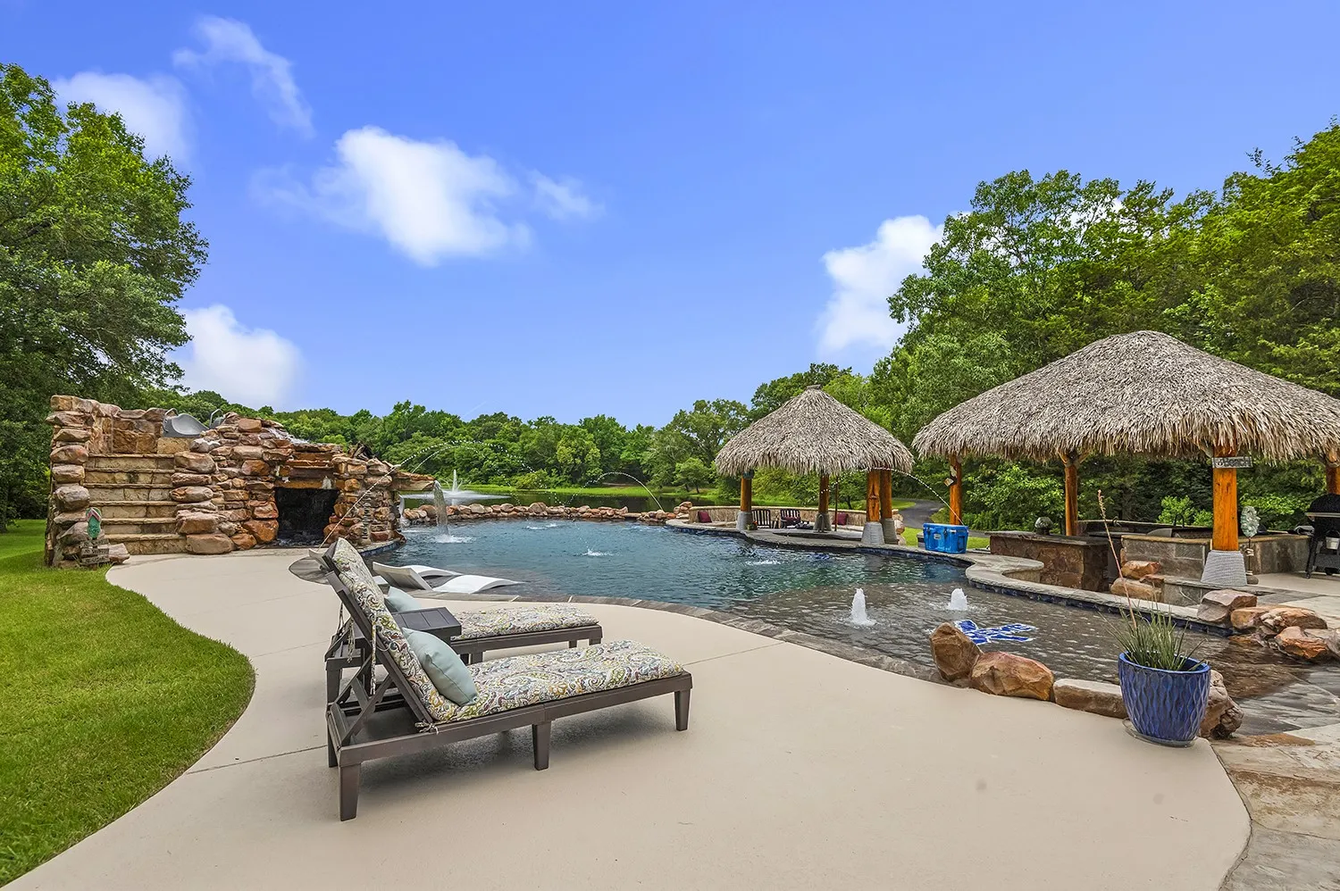 Expansive backyard oasis featuring a freeform swimming pool with integrated water features and a rock waterfall grotto